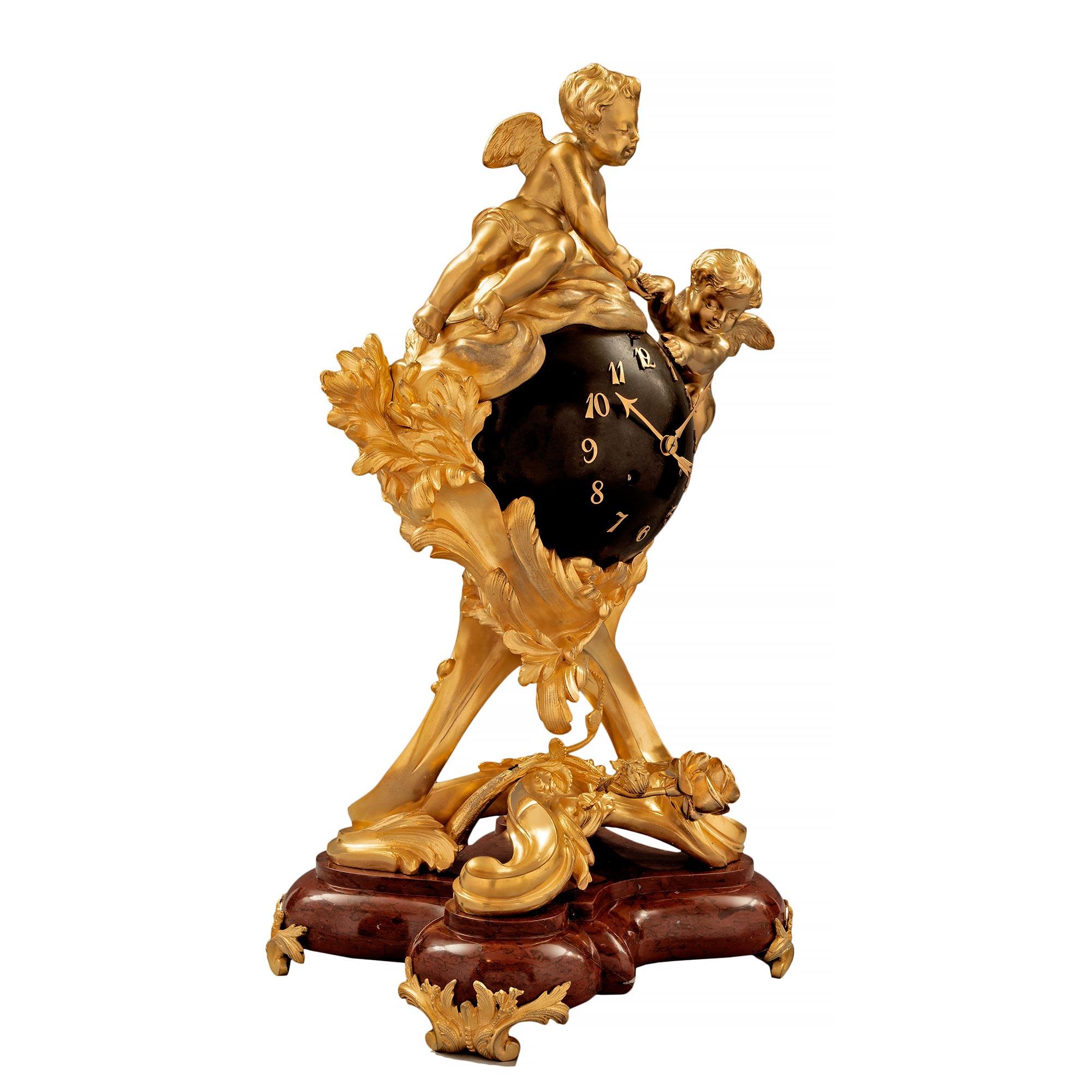 Eine atemberaubende und hochwertige französische Uhr aus dem 19. Jahrhundert aus Louis XV. St. Ormolu, patinierter Bronze und Rouge Griotte Marmor. Die Uhr steht auf einem äußerst dekorativen und einzigartig geformten dreieckigen