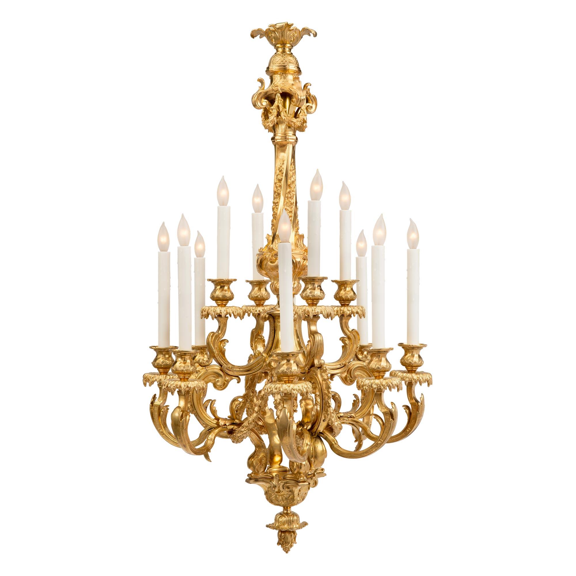A stunning French 19th century Louis XV st. ormolu twelve light chandelier. The chandelier is centered by a striking inverted bottom acorn finial below four richly chased dolphins. Branching out from the beautiful central cage are the twelve arms