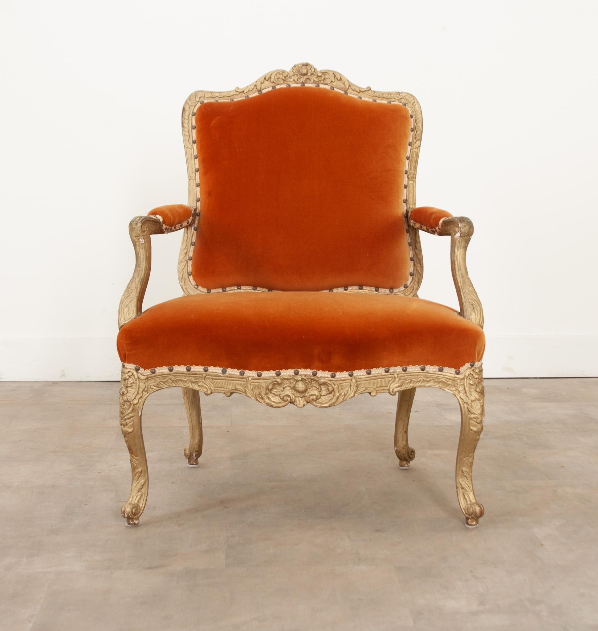 A fantastic and regal French Louis XV style painted fauteuil recently upholstered. The painted gold frames have been carved with exquisite craftsmanship and feature intricate cross hatch designs, florals, rosettes, acanthus leaves and vining. The