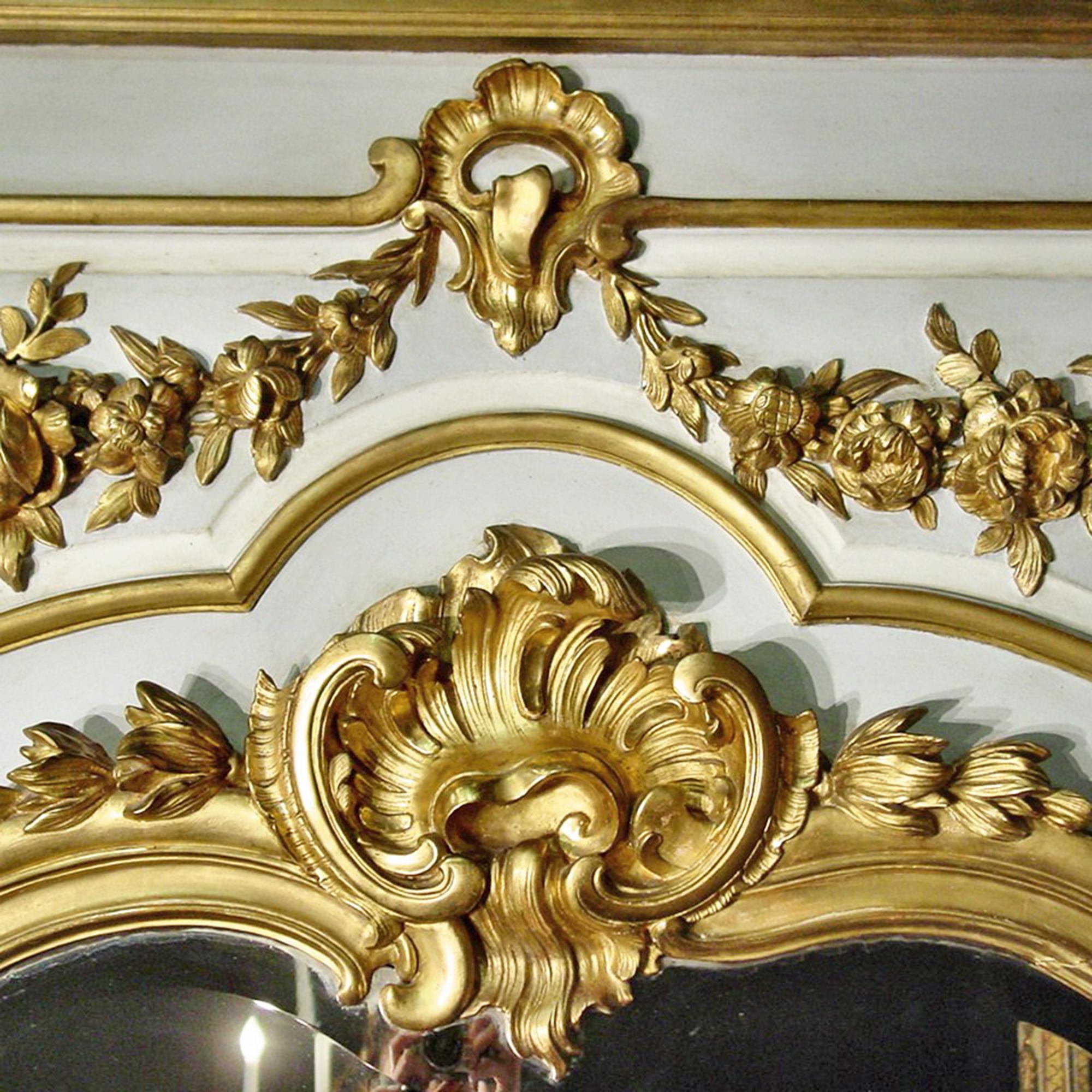 A Louis XV style patinated and giltwood boiseries element, 19th century, circa 1840. The rectangular panel is fitted with a shaped beveled mirror plate surrounded by giltwood borders incorporating Floral and foliate swags and surmounted by a shell