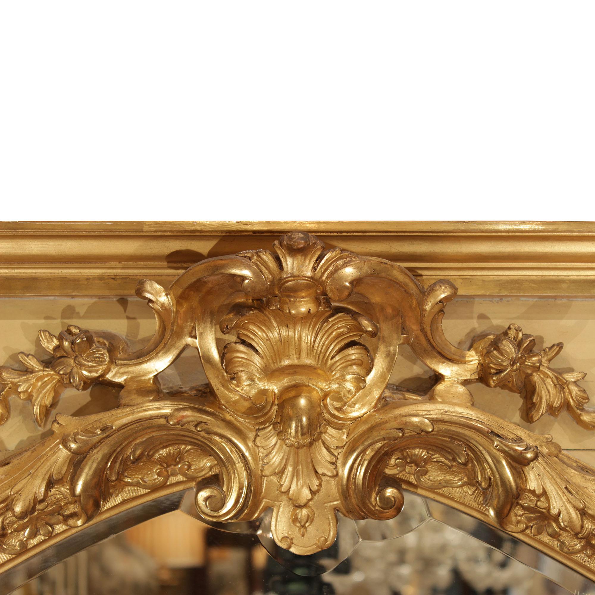 A very attractive French 19th century Louis XV st. patinated and giltwood mirror. The original beveled mirror plate is within a carved foliate giltwood border. A large central acanthus leaf scrolls down each side. The giltwood mottled edge top