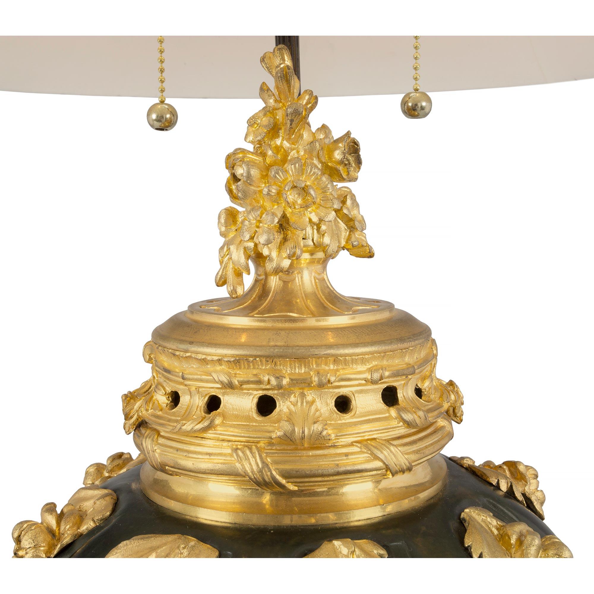 A striking French 19th century Louis XV st. patinated bronze and ormolu lamp. The lamp is raised by a richly chased rocaille designed ormolu base in a satin and burnished finish with foliate movements and cabochons. The patinated bronze body
