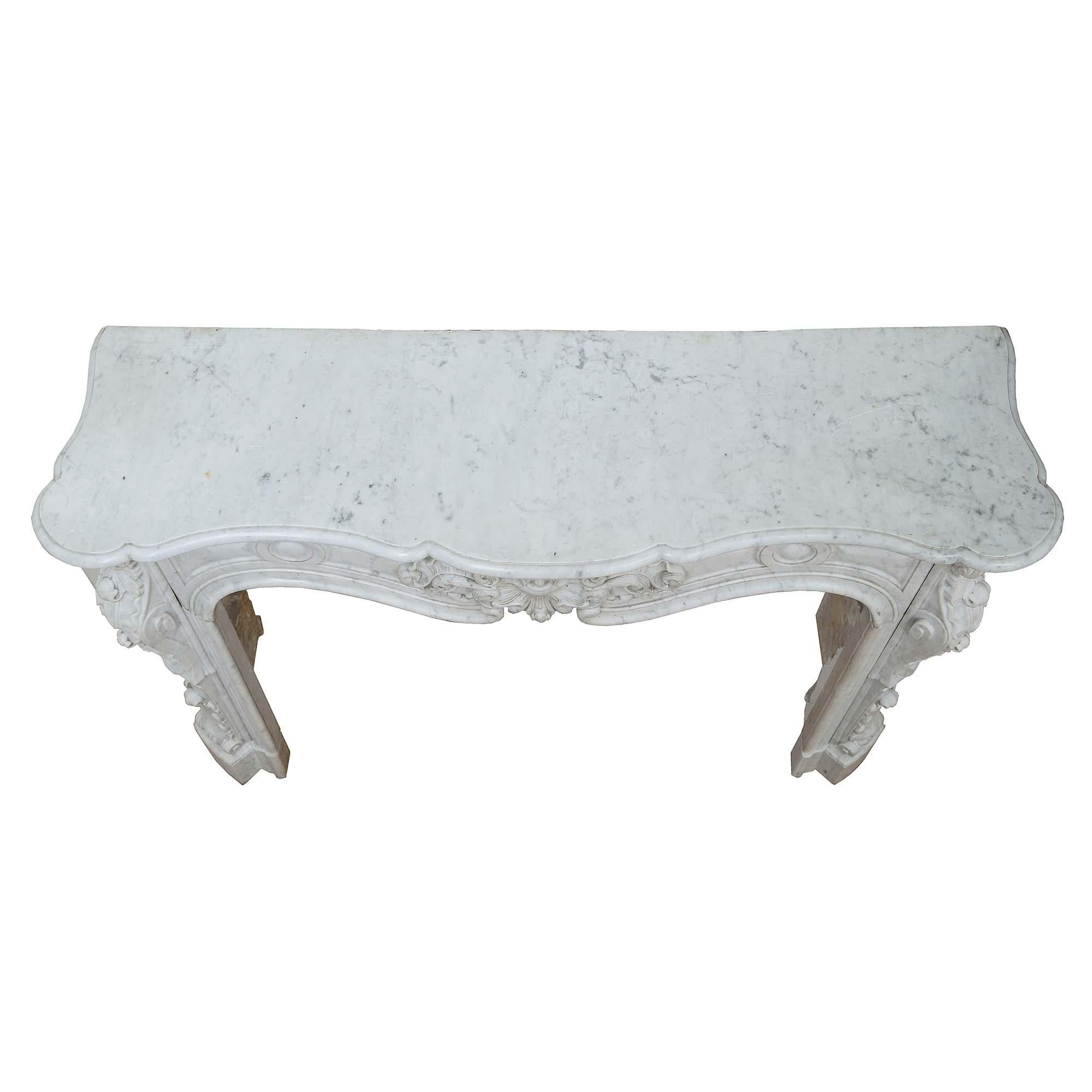 A magnificent French 19th century Louis XV st. white Carrara marble mantel. This exquisitely carved mantel is raised by volute jambs with rich carvings of large acanthus leaves and scrolls. The arbalest shaped frieze has an extremely well carved