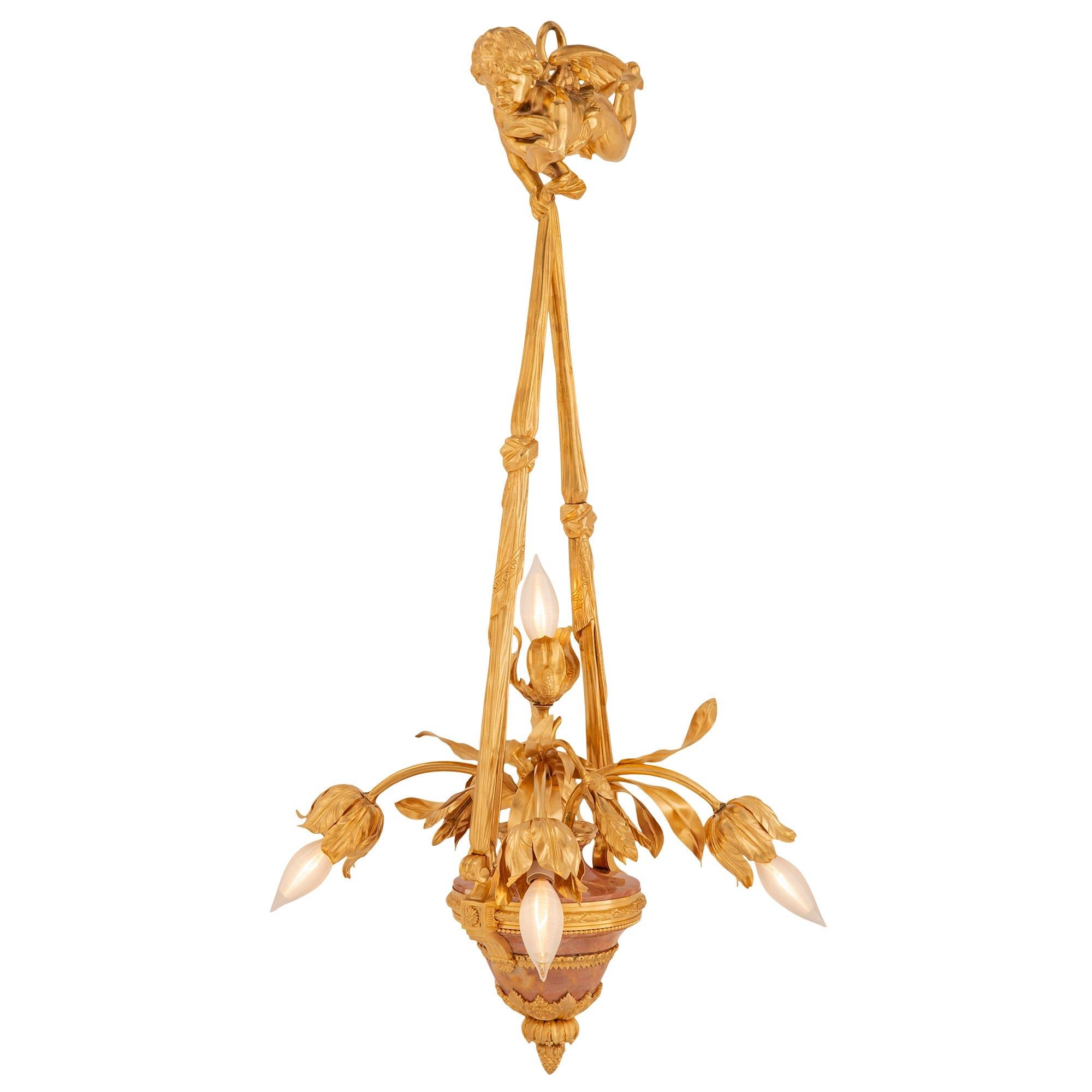 An exquisite and most decorative French 19th century Louis XVI Belle Époque period ormolu and marble chandelier. The five arm chandelier with lovely subject matter is centered by a bottom richly chased acorn finial amidst lovely finely detailed