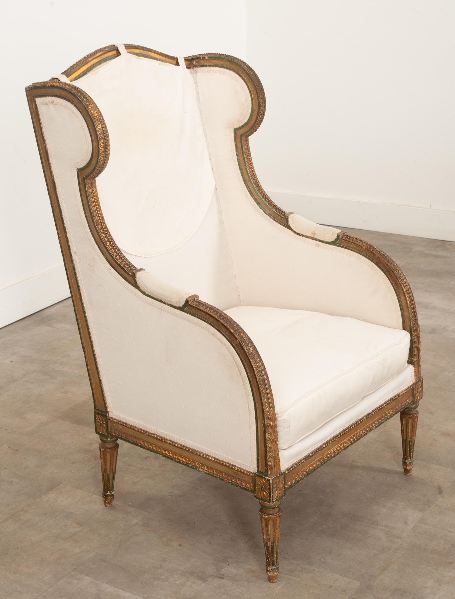 A French Louis XVI style carved and painted bergère à oreilles circa 1860 featuring charming details and vintage upholstery.  Elegant and eye-catching  this chair is as much a conversation piece as it is a comfortable seat. The bergère's upper rail