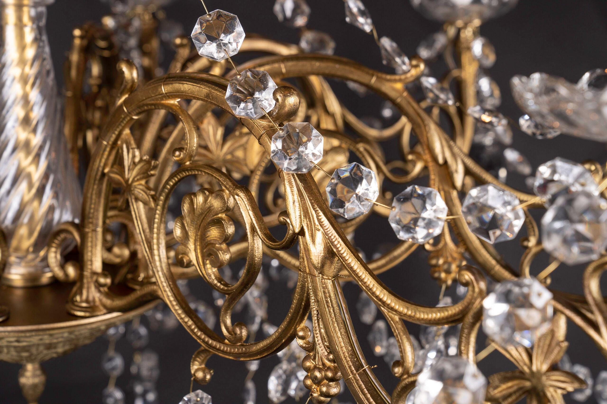 French 19th century Louis XVI bronze chandelier draped with ropes of octagon cut crystals and crystal plaquettes. The chandelier features a fine crystal center alongside crystal bobeches under the eight arms. Each arm features swirling details