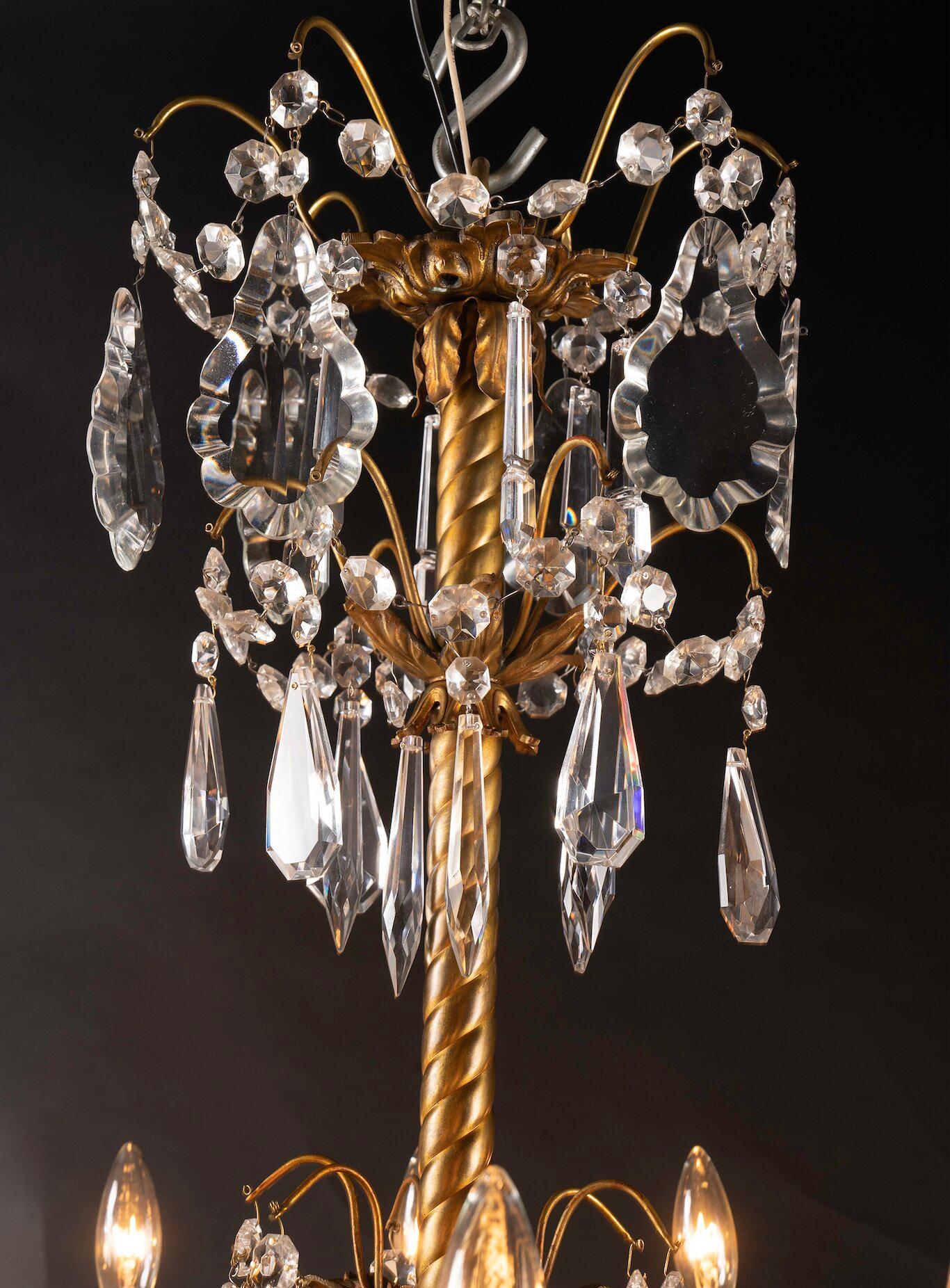 Questo splendido lampadario francese del XIX secolo Luigi XVI in bronzo e cristallo presenta due livelli di luci, 24 in totale. Il pezzo è drappeggiato con plaquette di cristallo, corde di cristalli tagliati a ottagono e bobeches di cristallo. Un