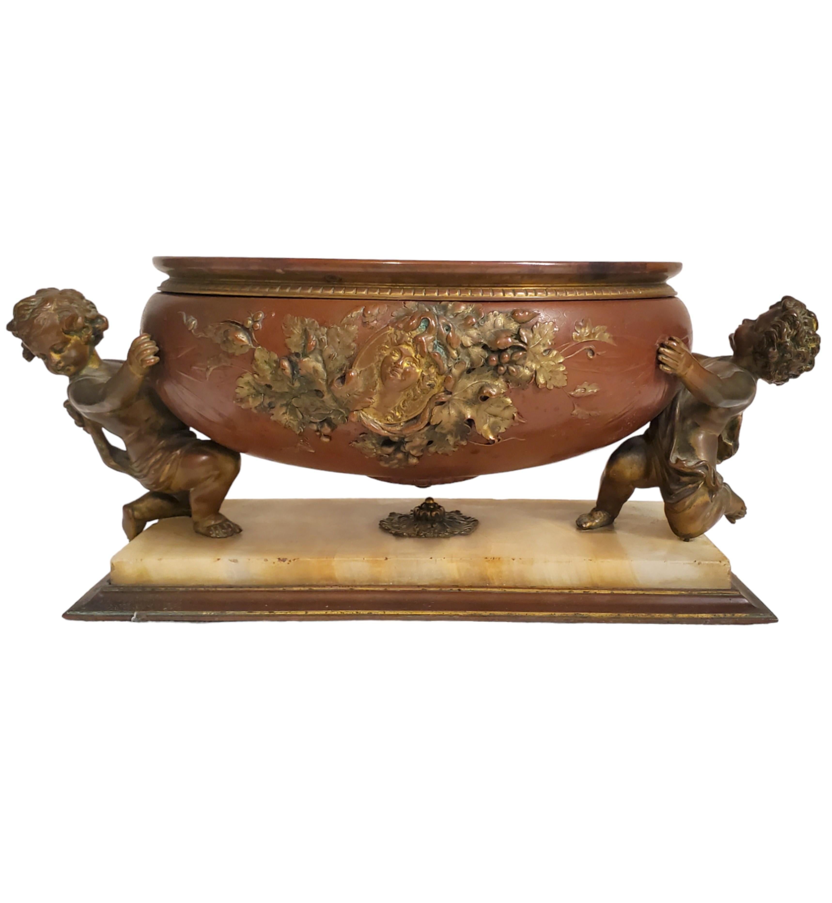 
An exquisite French 19th-century Louis XVI-style surtout de table 
featuring a centerpiece and two urns in patinated, gilded bronze and onyx, circa 1880.
 The oval centerpiece in amber patinated bronze, ormolu and onyx 
rests on a rectangular