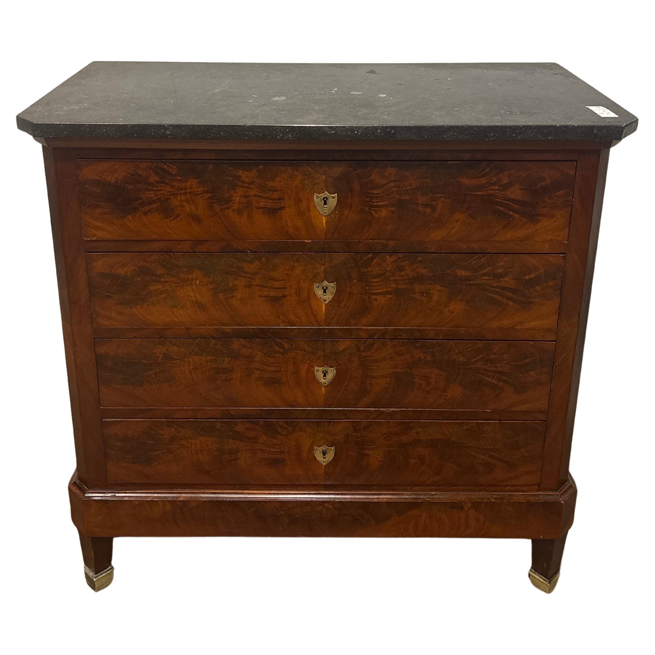 This wonderful Commode is made of flamed mahogany with a black marble top. It has bronze castor at the feet. 