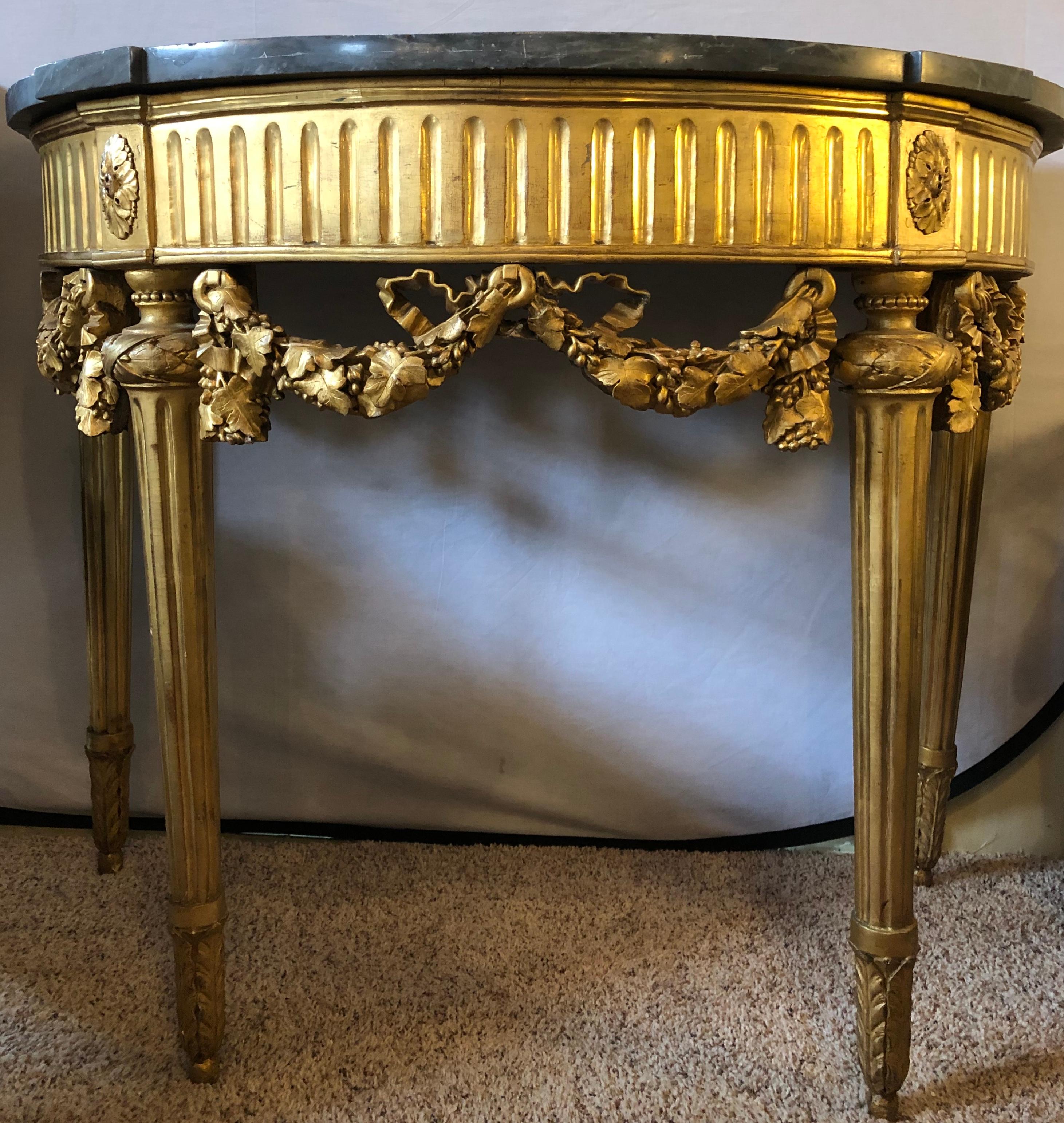 French 19th century Louis XVI console with marble top. This fine gilt console is simply stunning with its gray marble top supported by a ribbon and bow carved leaf design apron and group of four carved tapering legs, mid-late 19th century.
 