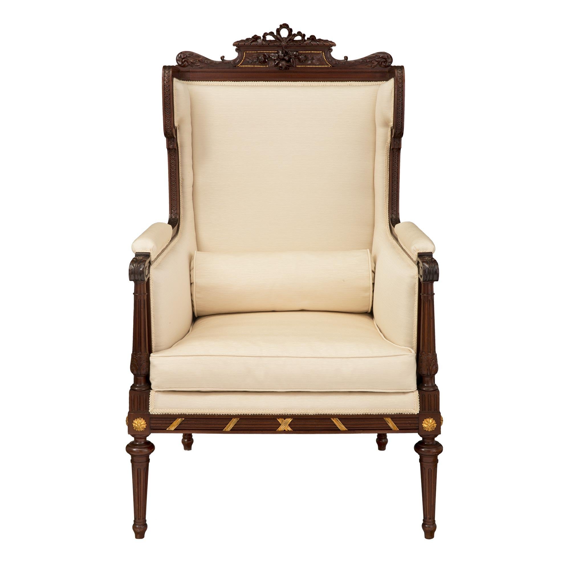 A most attractive French late 19th century Louis XVI st. Mahogany and ormolu mounted duchesse brisee, signed Jansen, Paris. The three piece lady's armchair is raised by tapered fluted legs below a moulded frieze. The frieze is adorned with an ormolu