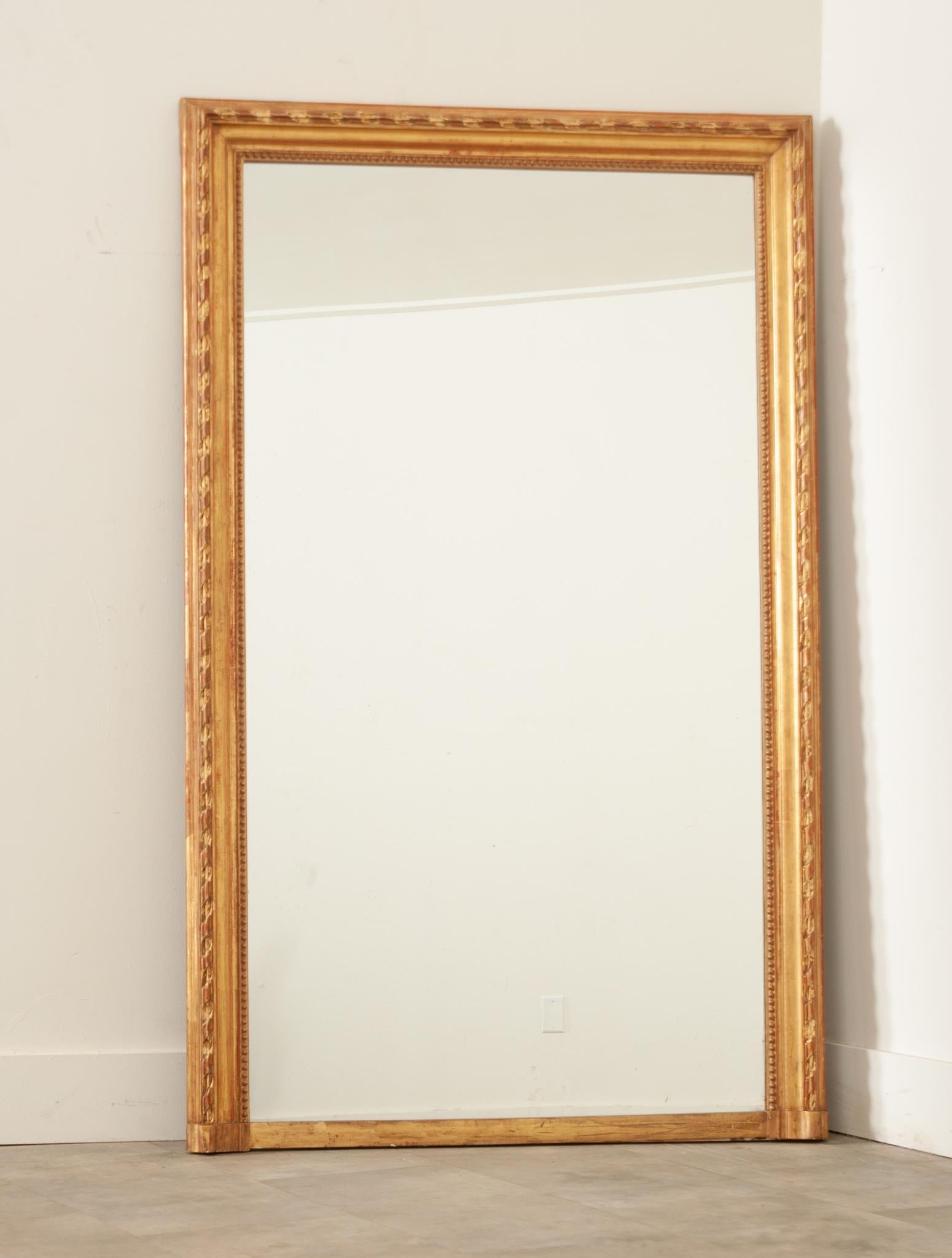 Ein feiner französischer Kaminsims-Spiegel im Louis-XVI-Stil, der im 19. Jahrhundert in Frankreich handgefertigt wurde. Der kunstvoll geschnitzte Rahmen aus vergoldetem Holz ist in ausgezeichnetem Zustand und reichlich patiniert. Der Rahmen ist mit