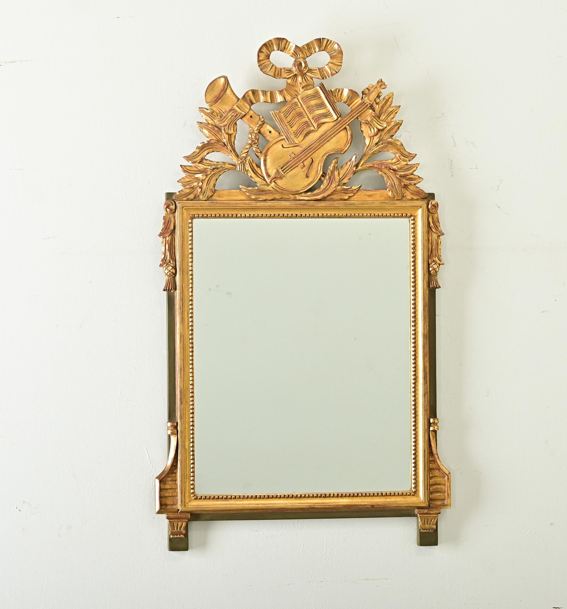 A charming music-themed giltwood trumeau mirror from France, circa 1870. Topping the piece is giltwood ornamentation of a dainty satin ribbon draped over carvings of a flute and violin, joined by open sheet music for a little duet in any room you