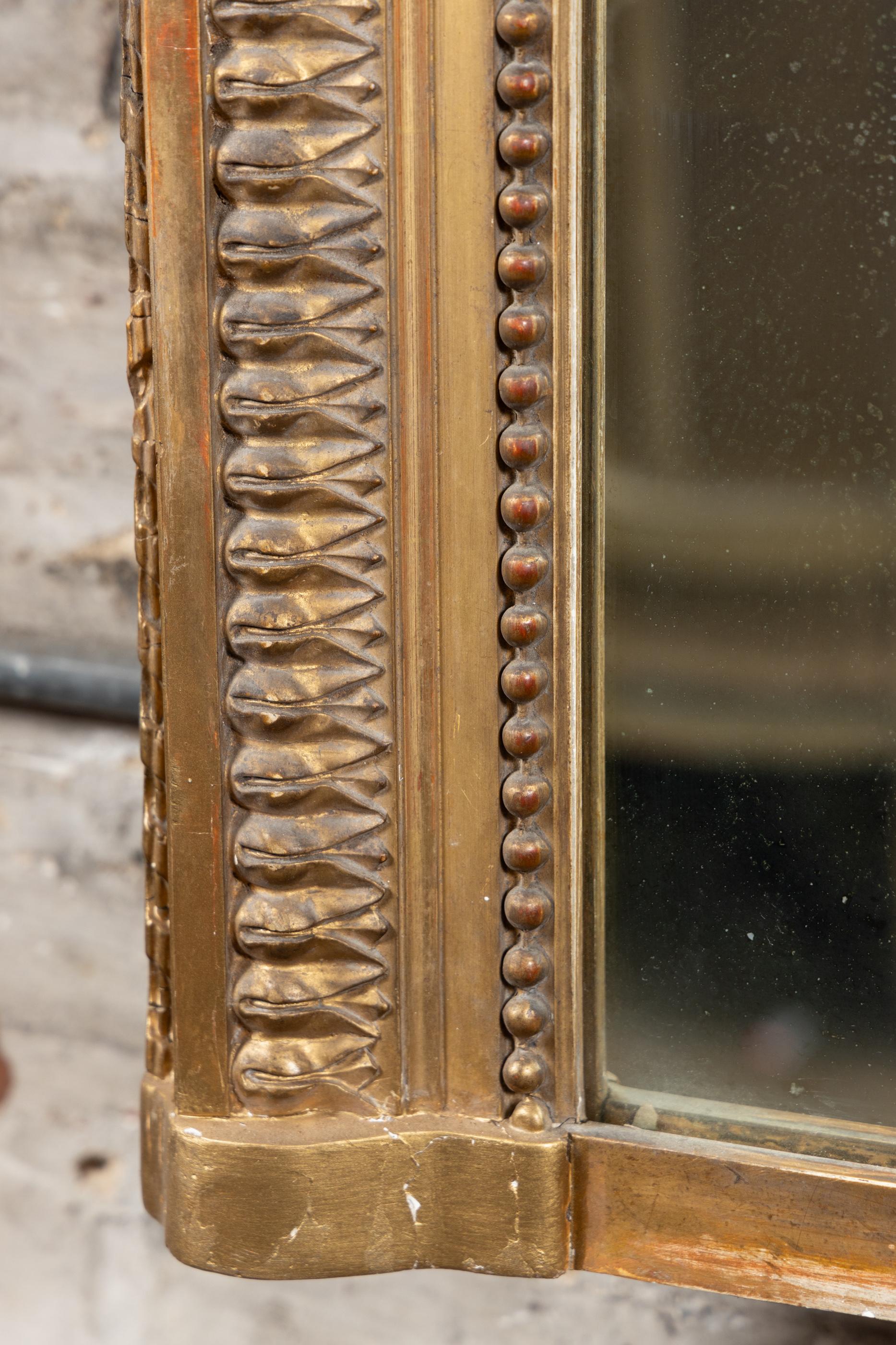 Ce magnifique miroir rectangulaire Louis XVI est doré à la feuille et date du 19ème siècle, vers 1880. La pièce est une combinaison de bois doré et de gesso doré. La partie supérieure de la pièce est ornée de magnifiques décorations feuillagées dans