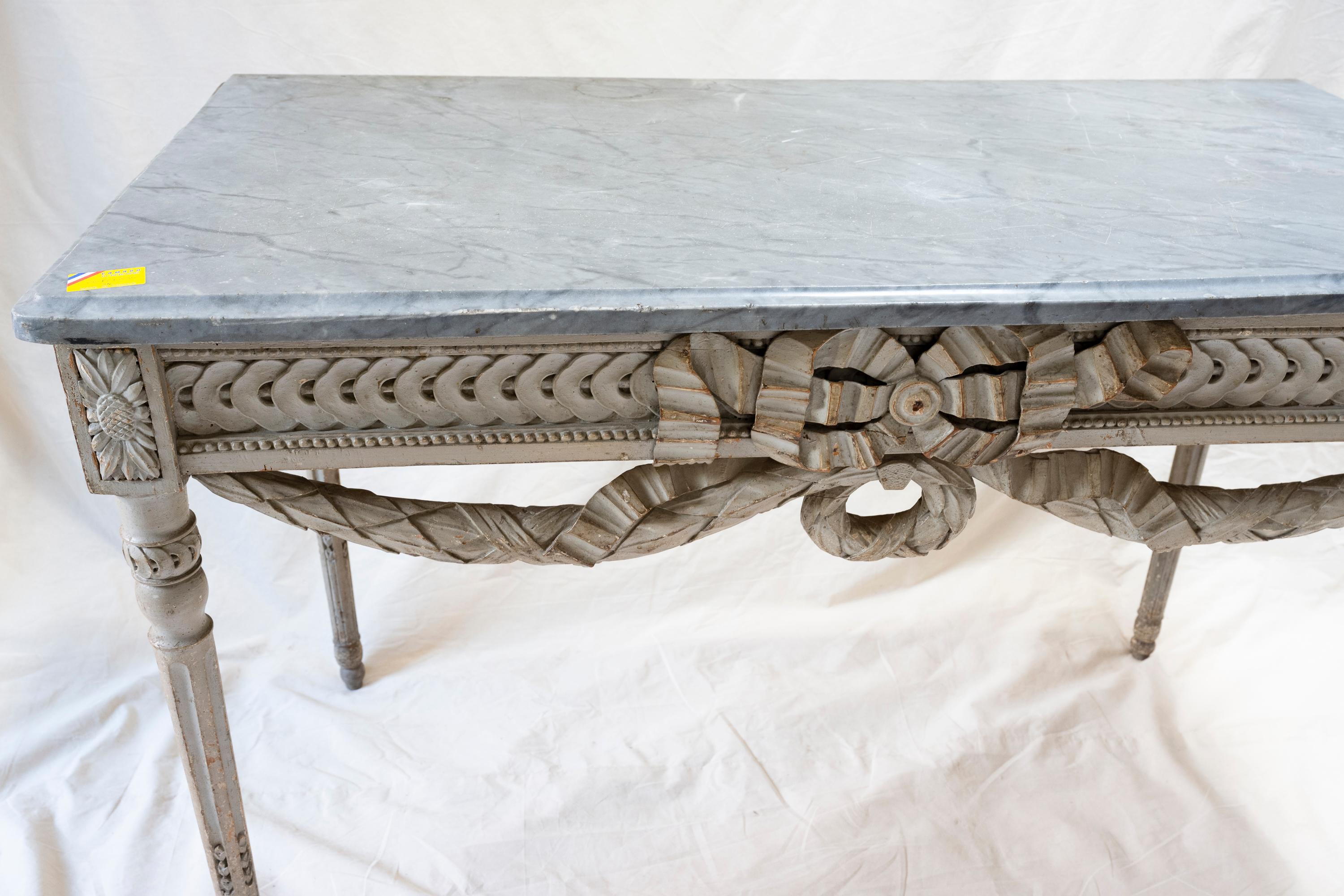 Louis XVI Console Table (c. 1850). Topped with Italian marble, this gray lacquered console table—with its ornate festoon embellishment—sat quietly in one of the salons in a family’s grand summer residence. 

Provenance: The summer castle of a