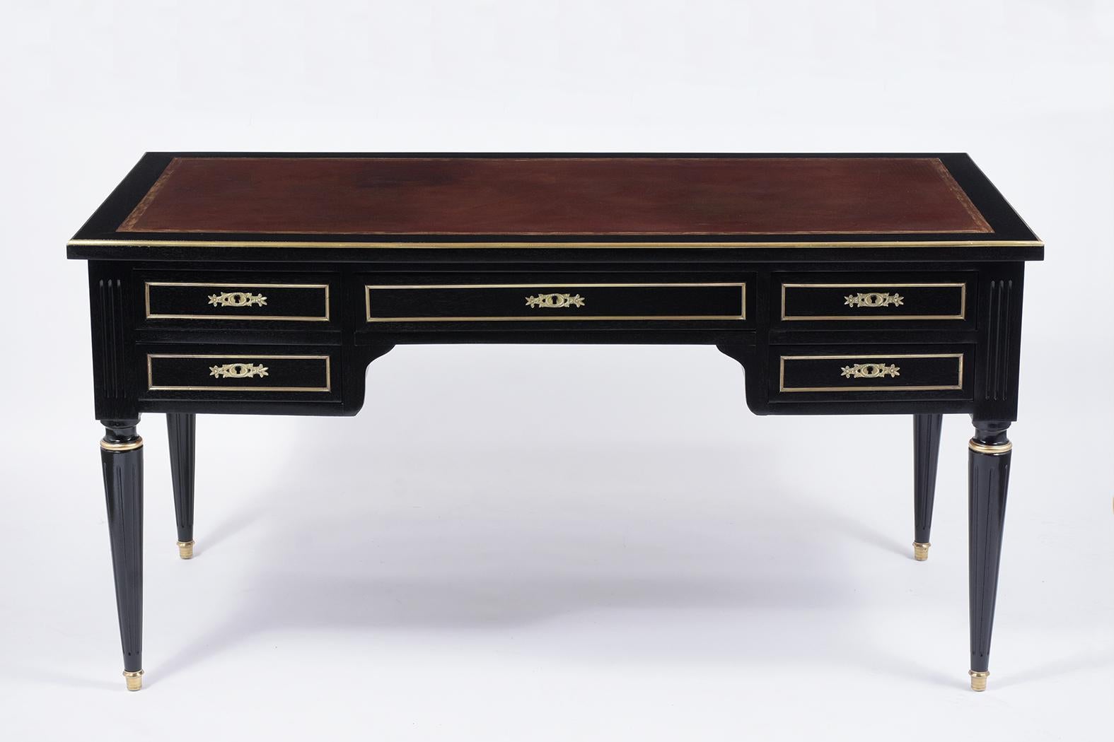 This French 1880s Louis XVI desk is handcrafted of mahogany wood stained a dark ebonized color with a beautiful newly lacquered finish. The top of the desk features original embossed leather newly dyed in Cordova color finish, gilt brass molding