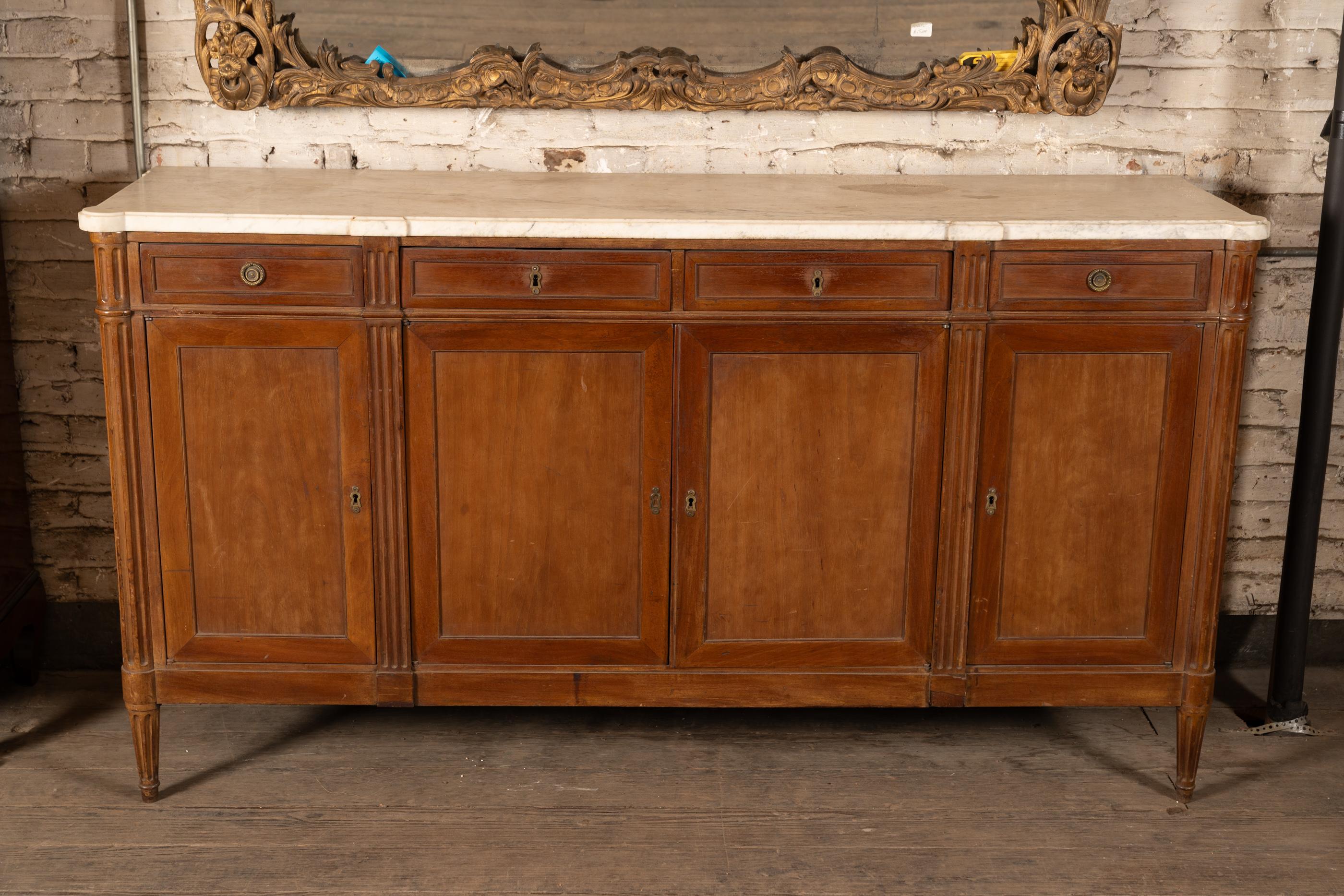 French 19th Century Louis XVI marble top buffet featuring fluted columns, four drawers at top, the outer two with circular pulls. Four doors are set on hinges. The piece sits on tapered fluted legs.

This piece is a collection of a fourth
