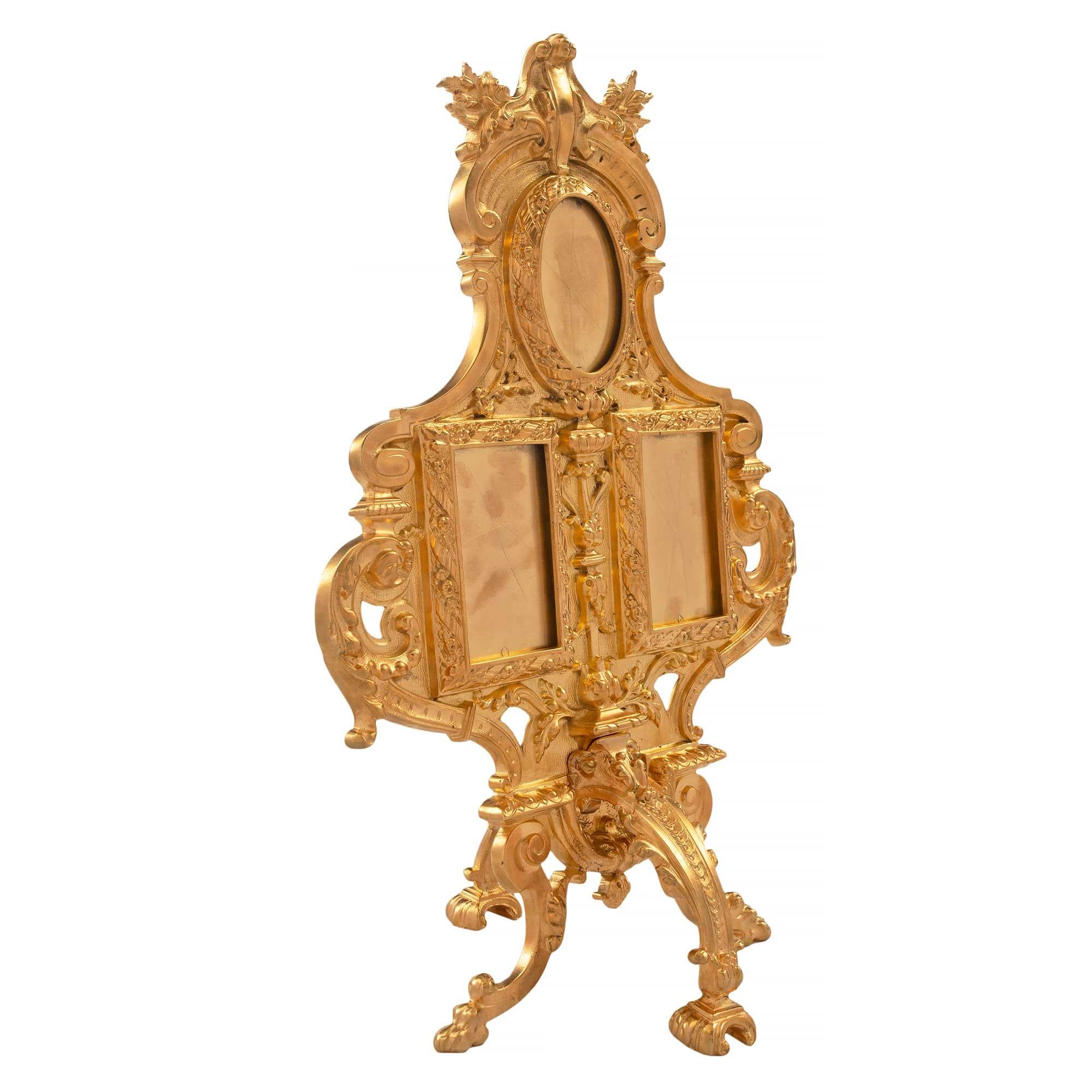 A uniquely shaped and most elegant French 19th century Louis XVI ormolu frame, that accommodates three pictures. The frame is raised by four curved legs with a 'Coeur de Rai' design. The two rectangular shaped frames are flanked by 'C' scrolled