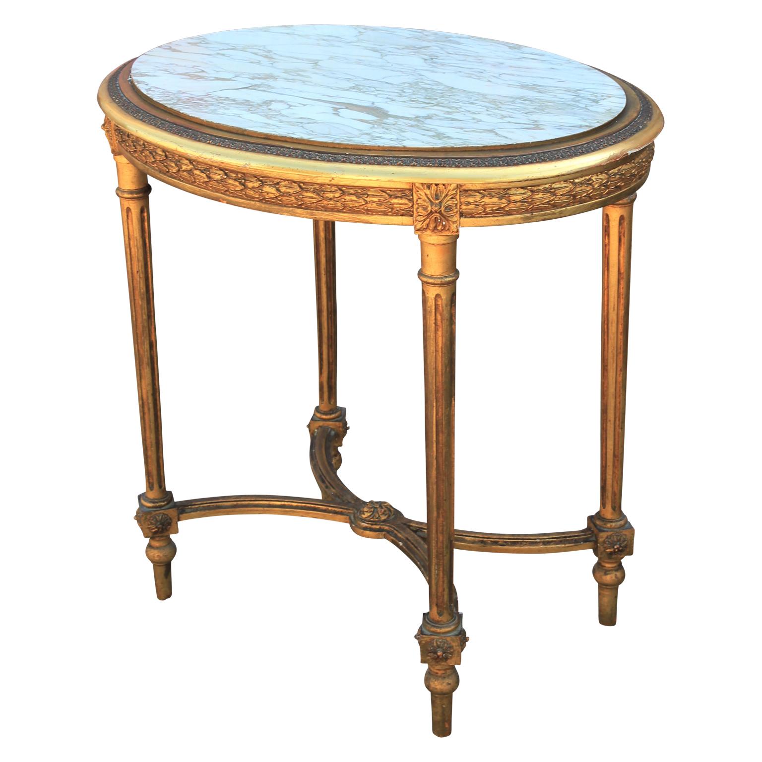 French Louis XVI period oval marble-top table, finished in fine gold gilt from the 19th century. This beautiful antique features an oval shaped brèche marble. The apron is decorated with carved motifs and square rosettes where the legs join the top.