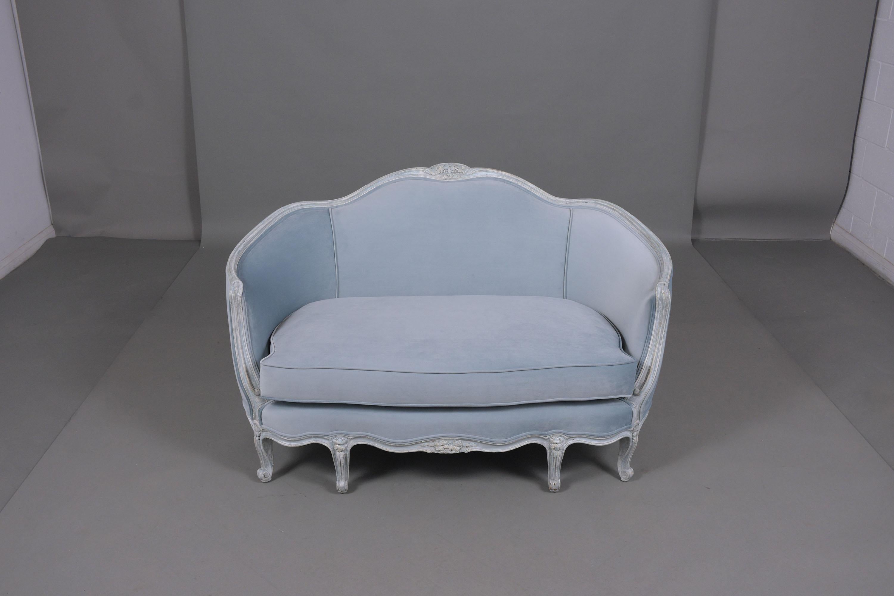 An extraordinary antique Louis XVI settee crafted out of wood fully restored by our craftsmen. This lovely piece has beautiful hand-carved details throughout the entire frame painted in a baby blue and oyster color with a unique distressed finish.