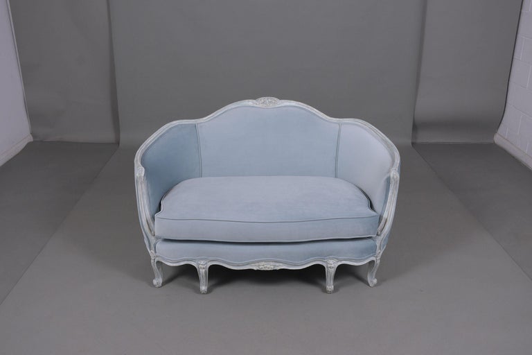 An extraordinary antique Louis XVI settee crafted out of wood fully restored by our craftsmen. This lovely piece has beautiful hand-carved details throughout the entire frame painted in a baby blue and oyster color with a unique distressed finish.