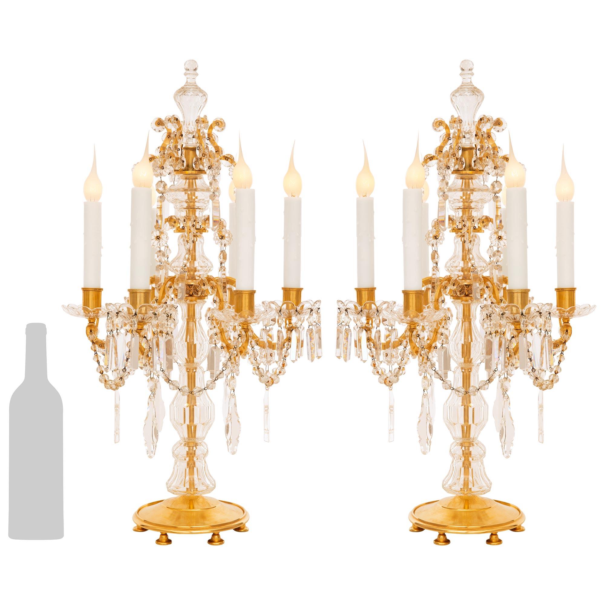 A stunning and tastefully decorated pair of French 19th  century Louis XVI st. Baccarat Crystal and Ormolu Girondole lamps. Each six light lamp is raised on a circular Ormolu base with a mottled edge and six flat feet beneath. The fut is encased in