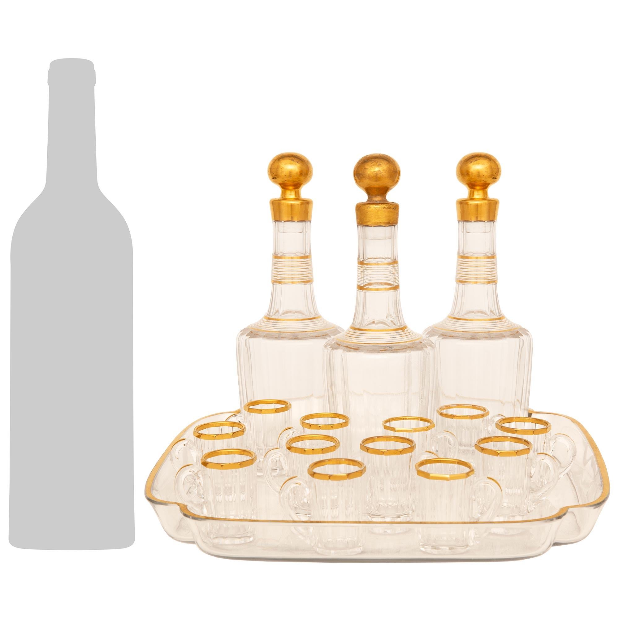 Eine schöne und sehr dekorative Französisch 19. Jahrhundert Louis XVI st. Baccarat Crystal Likör-Set. Dieses beeindruckende sechzehnteilige Set besteht aus einem quadratischen Tablett mit konkaven Ecken und einem vergoldeten Rand. Die zwölf