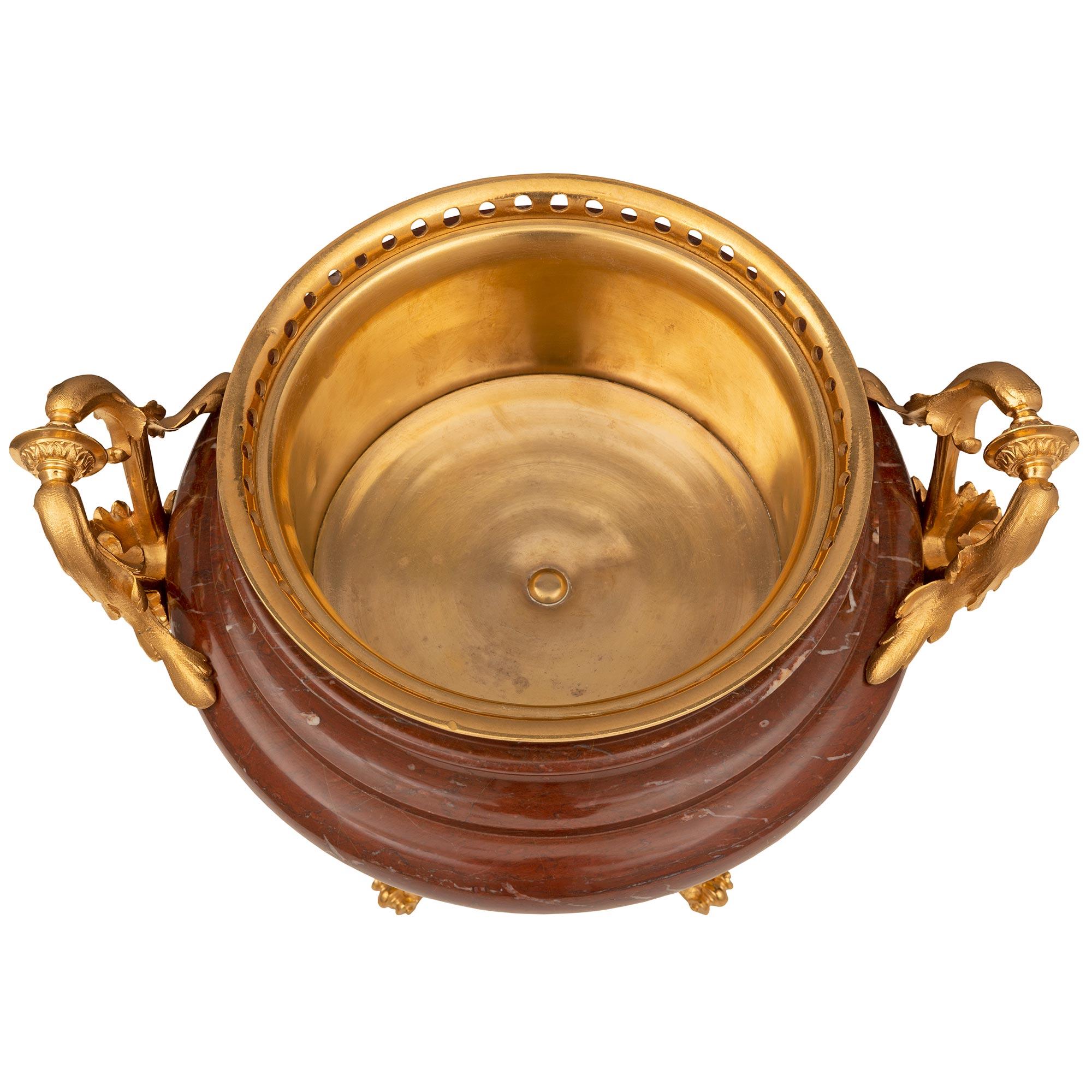 A most elegant French 19th century Louis XVI st. Belle Époque period ormolu and Rouge marble centerpiece. The centerpiece is raised by a unique and extremely decorative square base with recessed sides and finely detailed scrolled foliate ormolu