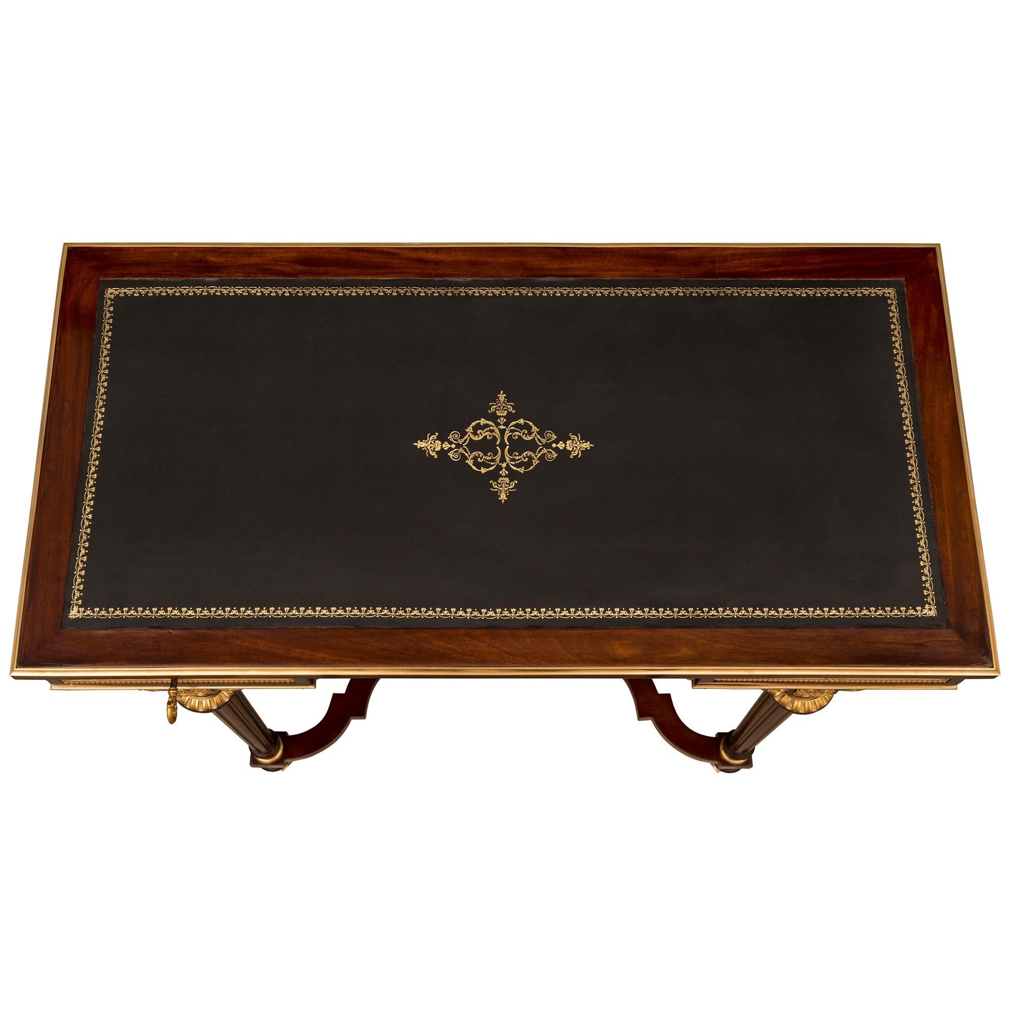 An elegant and most unique French 19th century Louis XVI st. Belle Epoque period mahogany, burl elm, and ormolu desk attributed to Maison Krieger. The two drawer desk is raised by circular tapered fluted legs with ormolu top and bottom caps, and