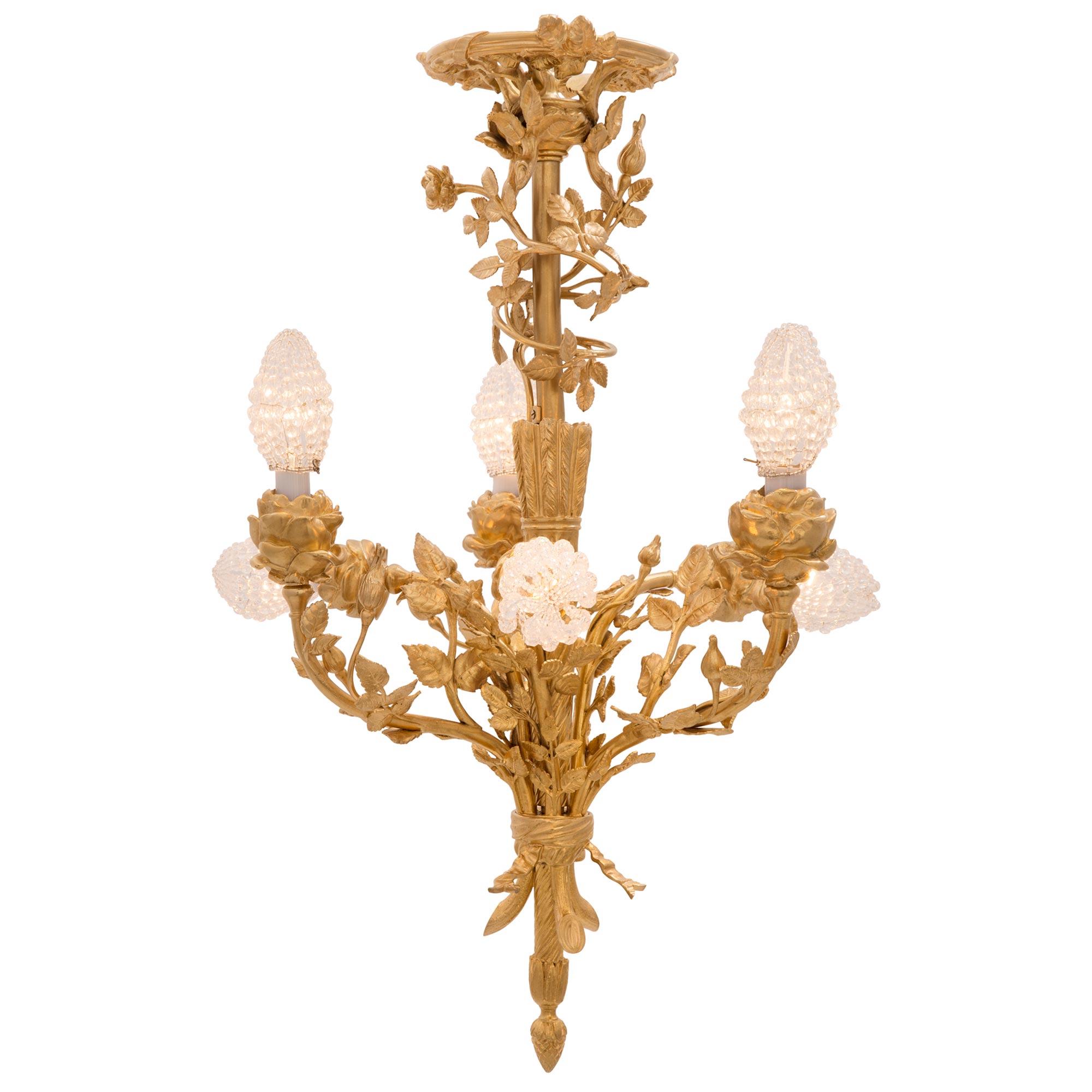 Un très élégant lustre français du 19ème siècle de style Louis XVI et de la période Belle Époque en bronze doré. Le lustre à six bras est centré par un magnifique épi de gland sous le fut central cannelé en spirale circulaire. Les six bras
