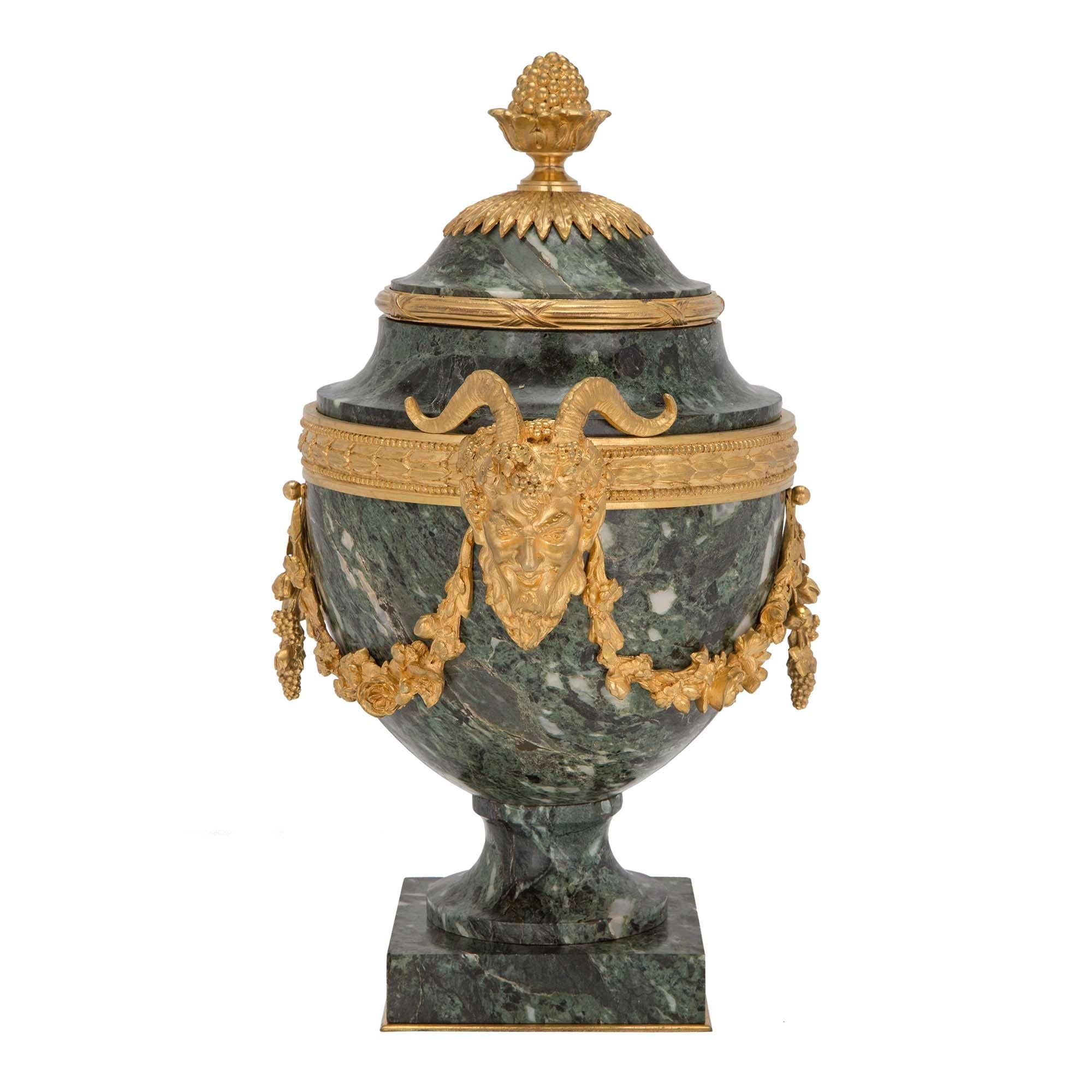A very elegant pair of French 19th century Louis XVI st. Belle Époque period Vert Antique marble and ormolu urns. Each urn is raised by a square marble base with ormolu trim, and marble socle. The marble body displays a striking richly chased satyr