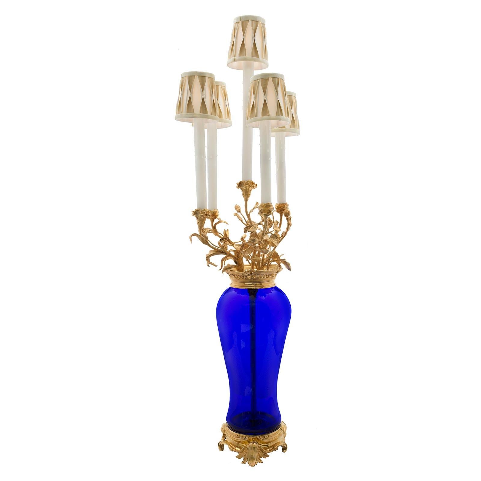 Un beau candélabre français du 19ème siècle de style Louis XVI soufflé à la main en verre bleu cobalt et ormolu monté en lampe. La lampe est surélevée par une élégante base en bronze doré à motifs feuillus, sous le corps élancé en verre bleu cobalt