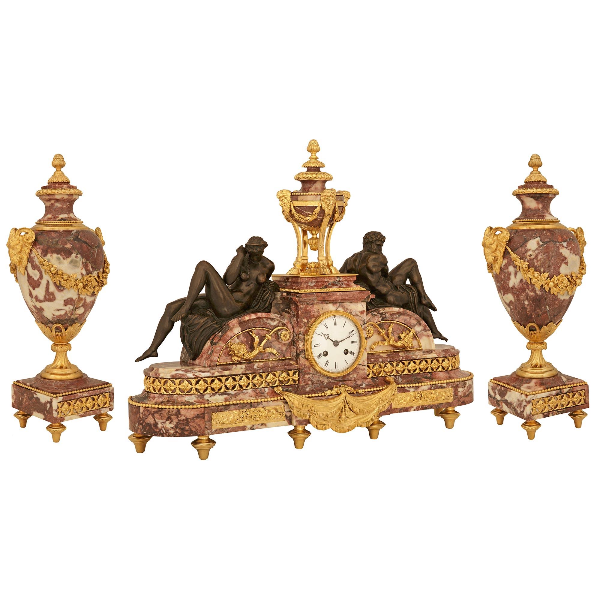 A most spectacular and high quality French 19th century Louis XVI st. patinated Bronze, Rouge Royal marble and Ormolu garniture set. This most striking garniture set consists of a central clock and a pair of lidded urns. The clock is raised by six