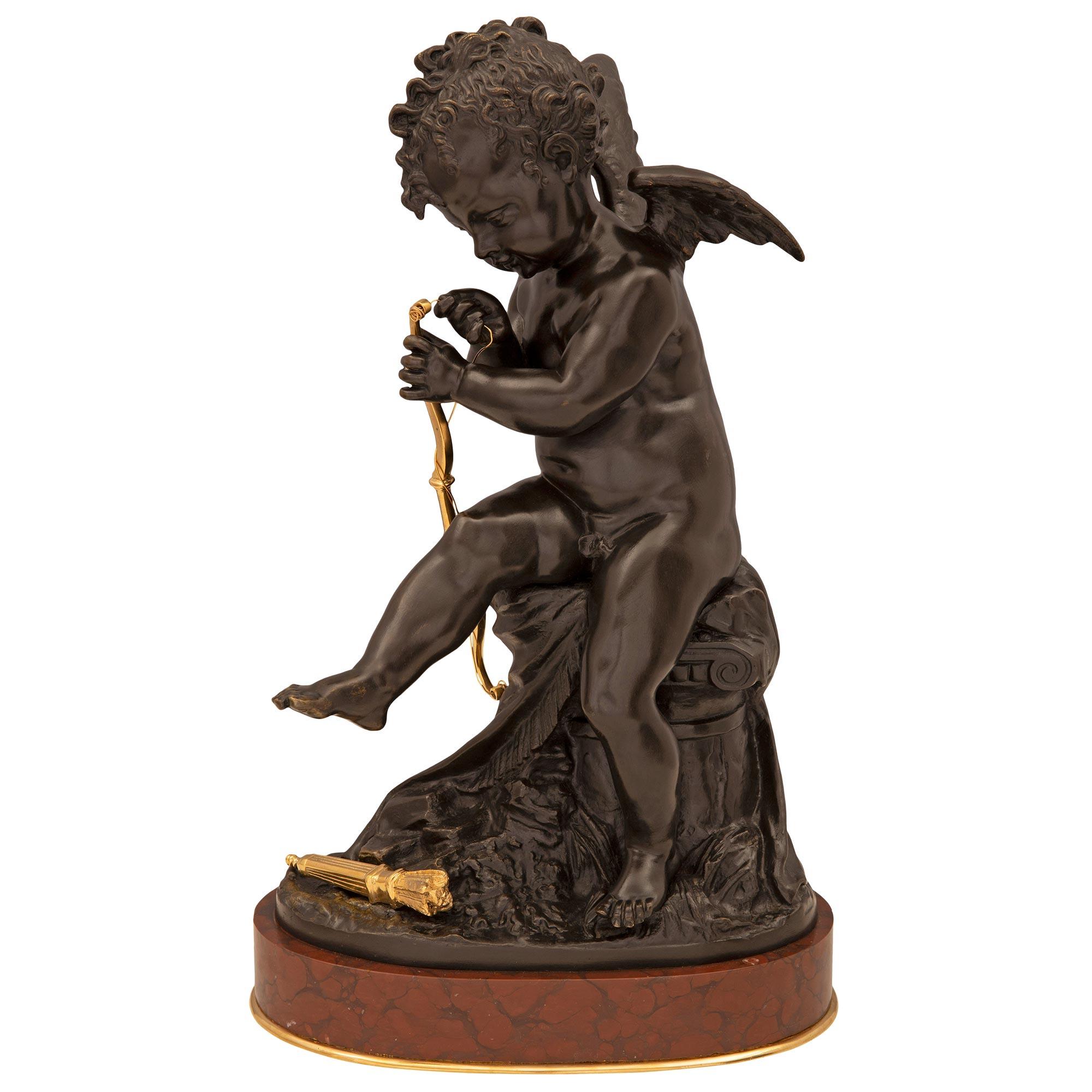 A charming and very elegant French 19th century Louis XVI st. patinated bronze, ormolu, and Rouge Griotte marble statue of a cherub signed Lemire. The statue is raised on an oval Rouge Griotte marble above a fine ormolu band. Above is the charming