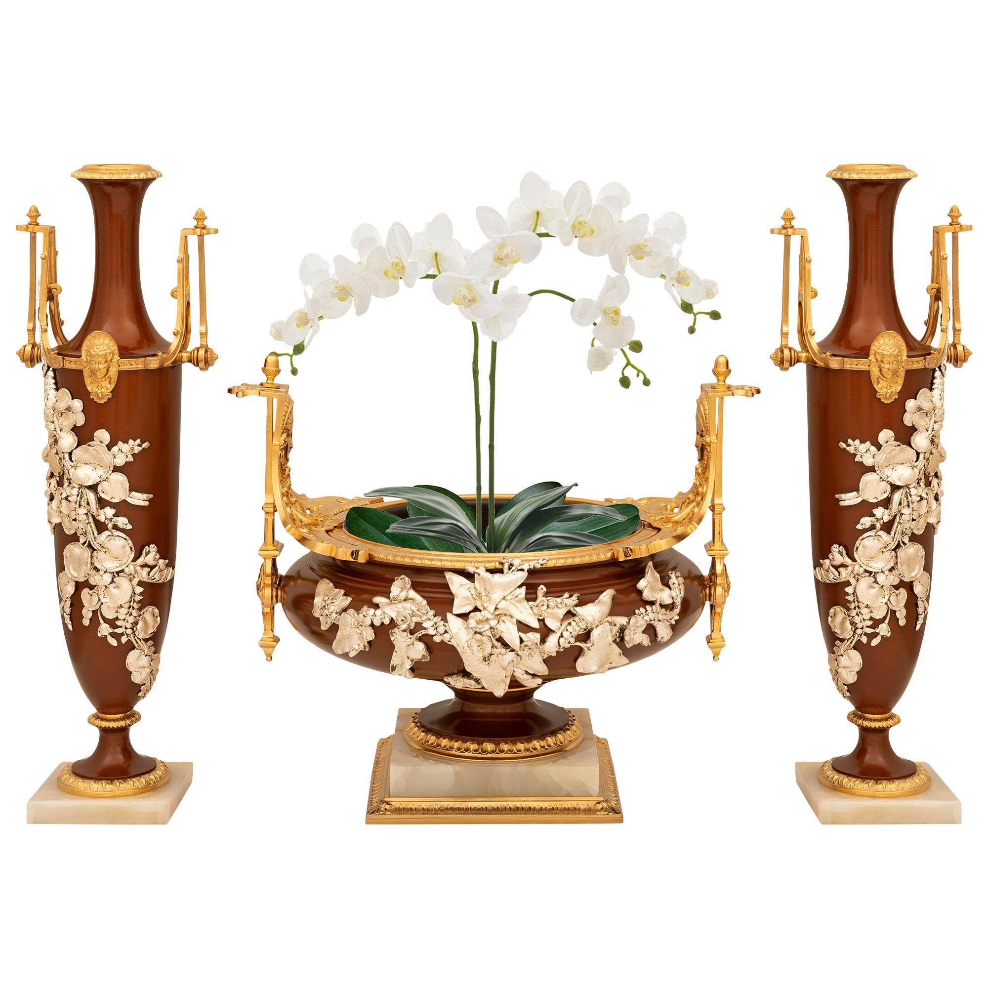 
Uno splendido e pregiato set da regalo francese del XIX secolo in bronzo smaltato, bronzo argentato, onice e ormolu. Questo elegantissimo set di tre pezzi poggia su basi quadrate in onice, con il centro che presenta una fascia scanalata e foliata
