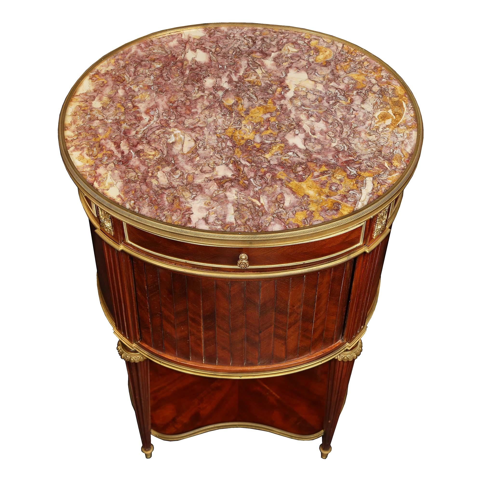 A very important French 19th century Louis XVI St. solid mahogany oval side table signed Brevete, circa 1880. The table is raised by four circular tapered fluted legs with ormolu sabots topped with ormolu bands. The legs are joined by a