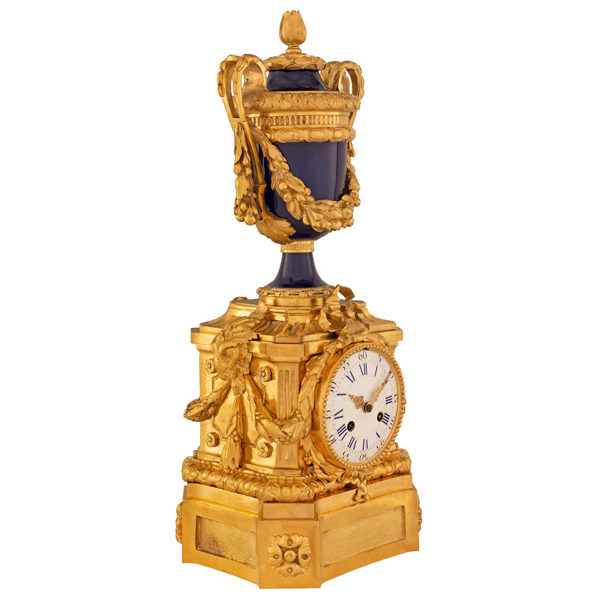 A striking and most elegant French 19th century Louis XVI st. cobalt blue porcelain and ormolu clock. The clock is raised by a square ormolu base with cut corners with fine rosettes and recessed hammered plaques. At the center is the striking white