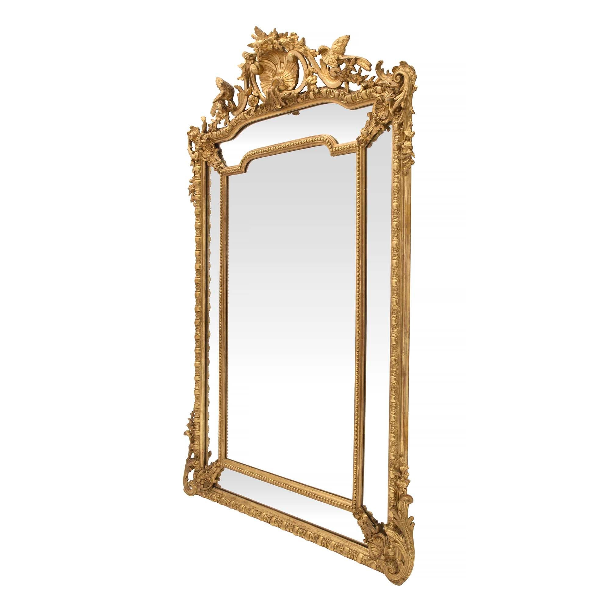 A stunning French 19th century Louis XVI st. double framed giltwood mirror. The original central mirror plate is framed within a beaded giltwood frame. The original outer mirror plates are framed by richly carved corner mounts amidst large elegant