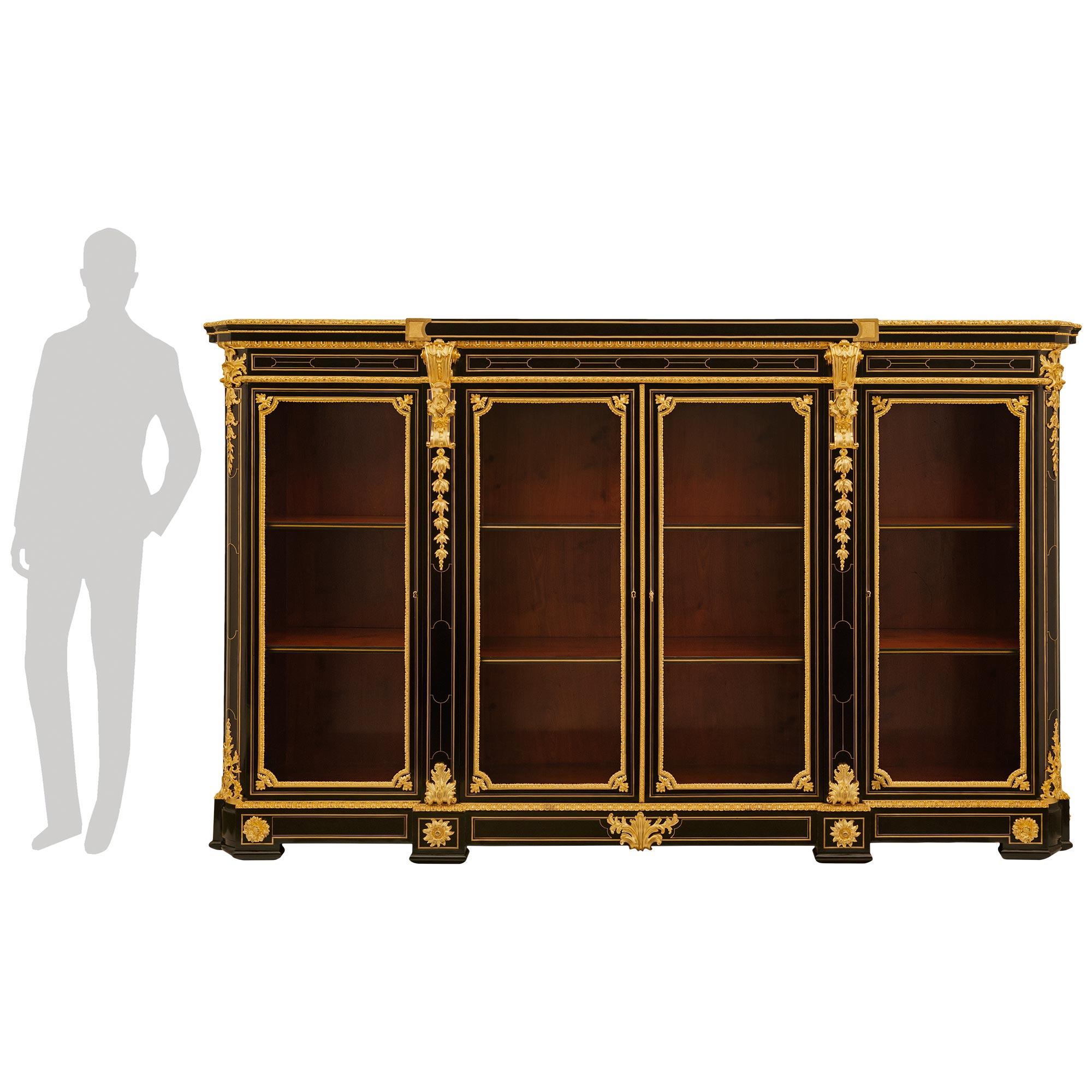 A sensational and most impressive French 19th century Louis XVI st. Ebony and Ormolu Boulle vitrine. This stunning four door vitrine is raised on a rectangular plinth centered by an ornate Ormolu palmette mount and decorated with exquisitely chased
