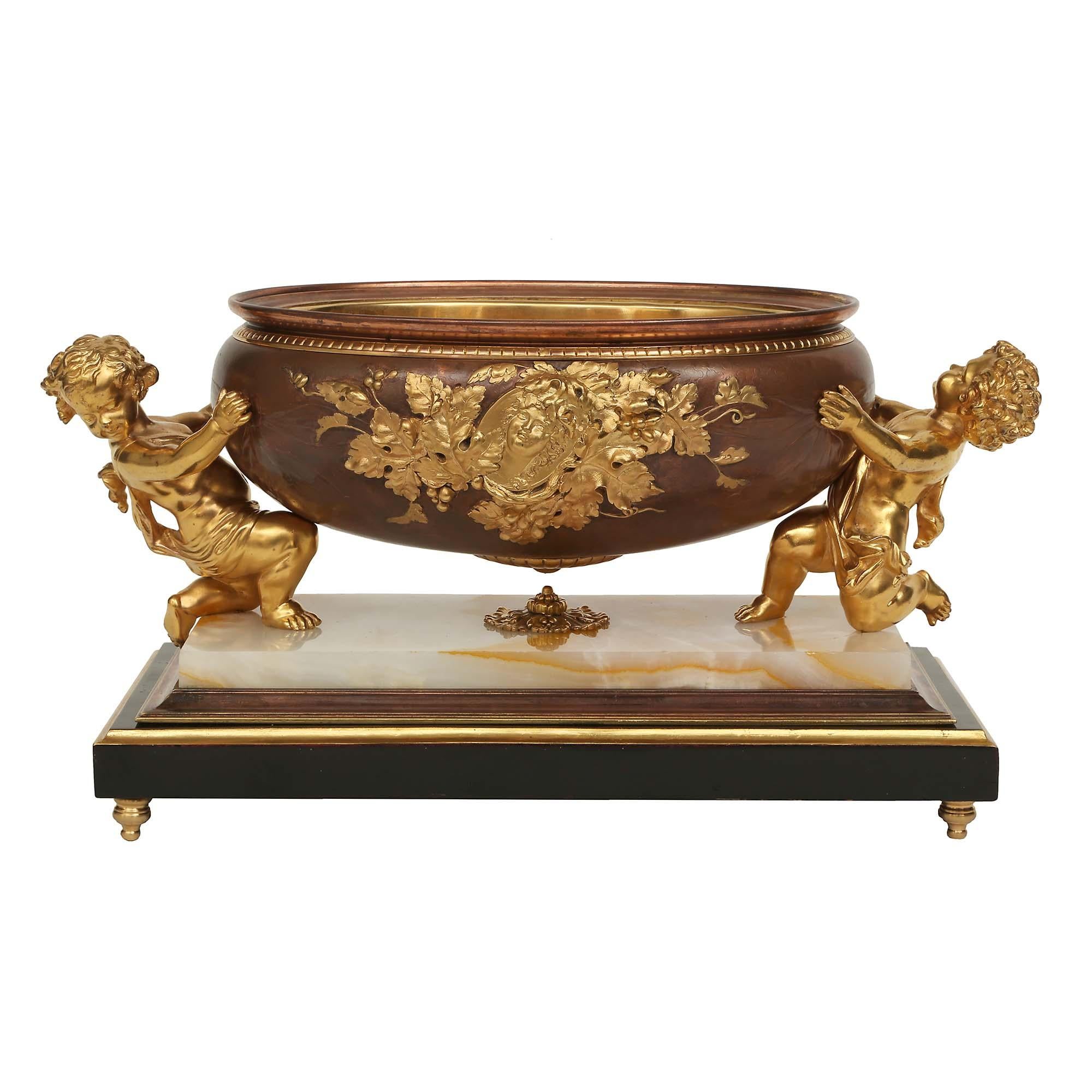 A charming and high quality French 19th century Louis XVI st. ebonized Fruitwood, onyx, patinated bronze and ormolu centerpiece bowl. The centerpiece is raised by four most elegant topie shaped feet below a rectangular ebonized fruitwood base with a