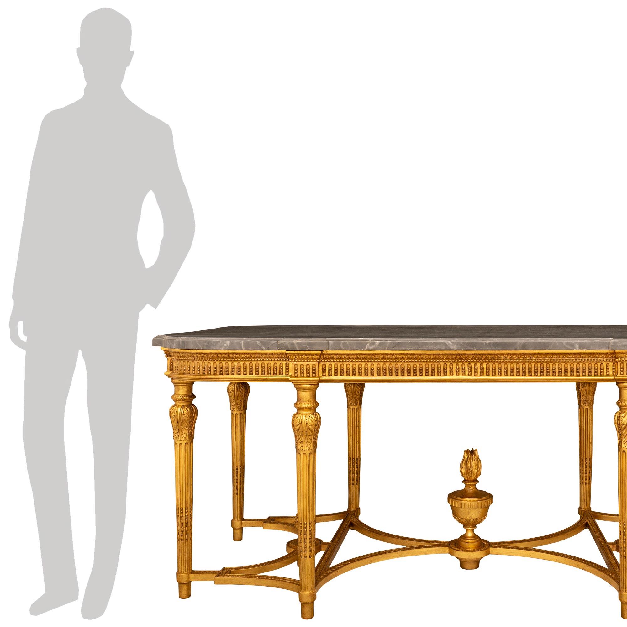 A striking and most decorative French 19th century Louis XVI st. Giltwood and Gris St. Anne marble center table. This rectangular shaped center table is raised by eight most unique circular fluted tapered fluted legs with beautifully carved berried
