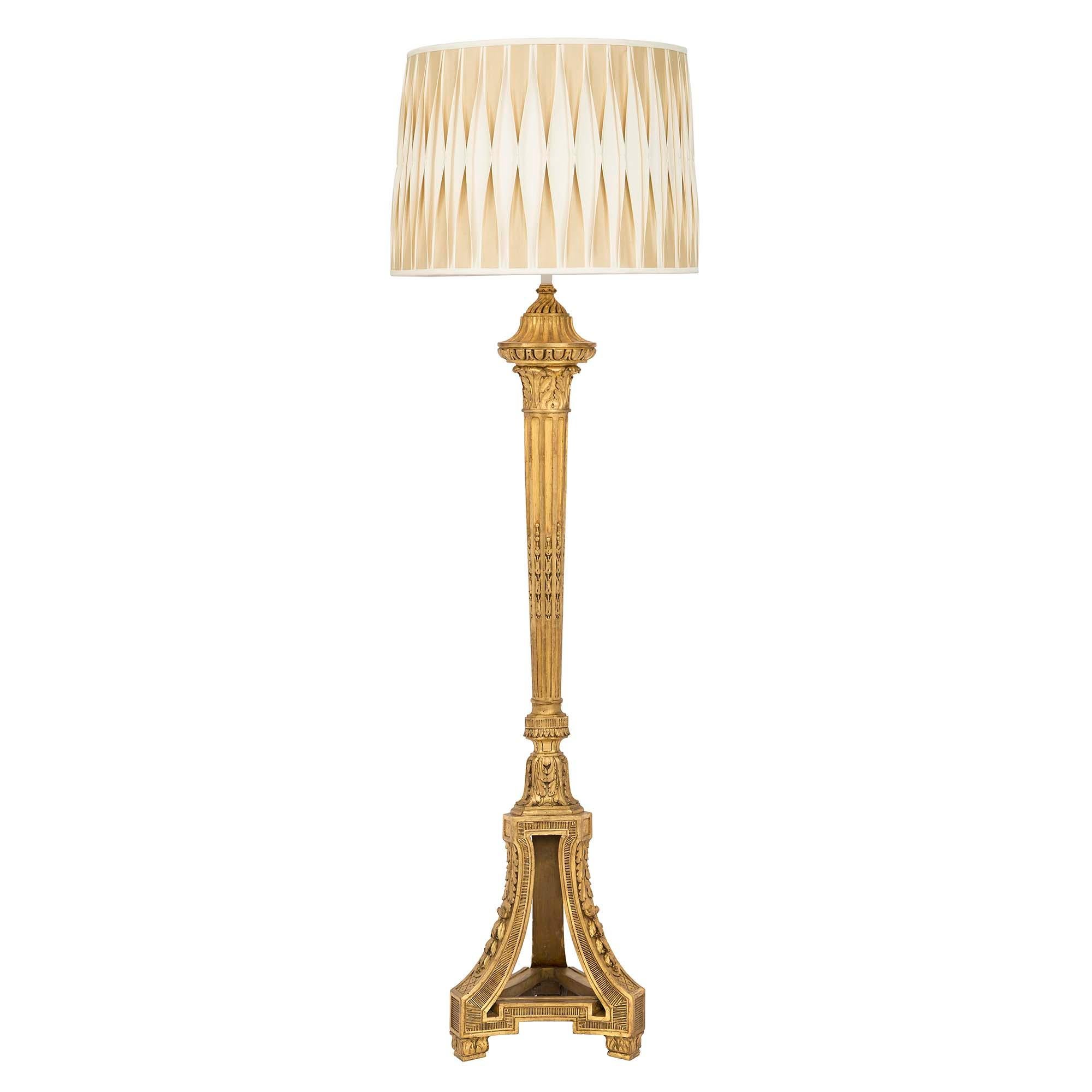 A superb French 19th century Louis XVI st. giltwood floor lamp. The floor lamp is raised by acanthus leaf block feet below a triangular shaped base with open concave sides. The base is decorated with fine fluted patterns, acanthus leaves, berried