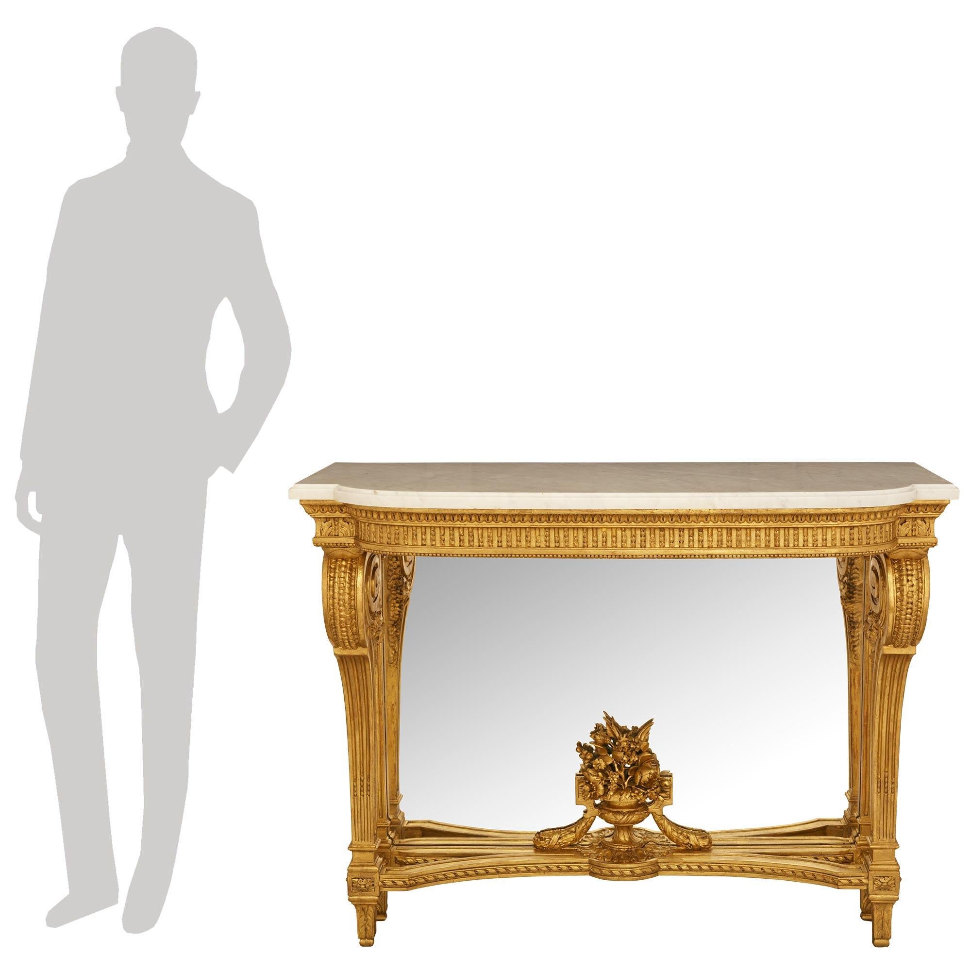 An elegant and most decorative French mid 19th century Louis XVI st. Giltwood, Mirror and white Carrara marble console. This stunning mirrored console is raised on four square tapered legs decorated with acanthus leaves below blocks with carved