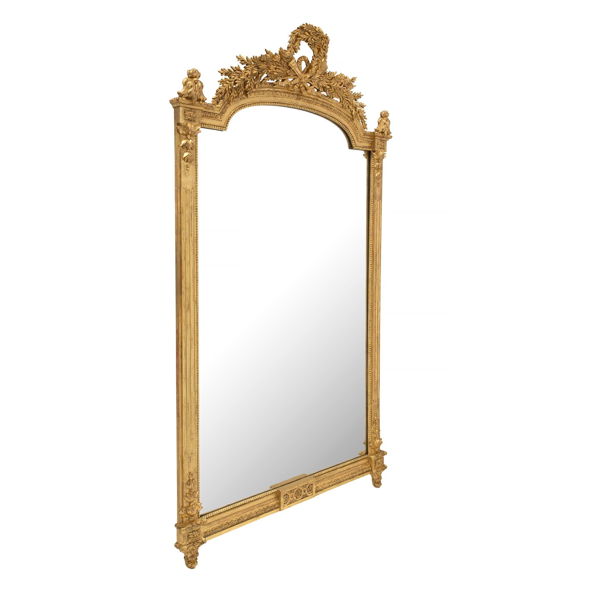 A most elegant French 19th century Louis XVI st. giltwood mirror. The original mirror plate is framed within a beaded giltwood border with Fine flutes along each side. Each corner displays Fine block rosettes with beautiful floral finials and