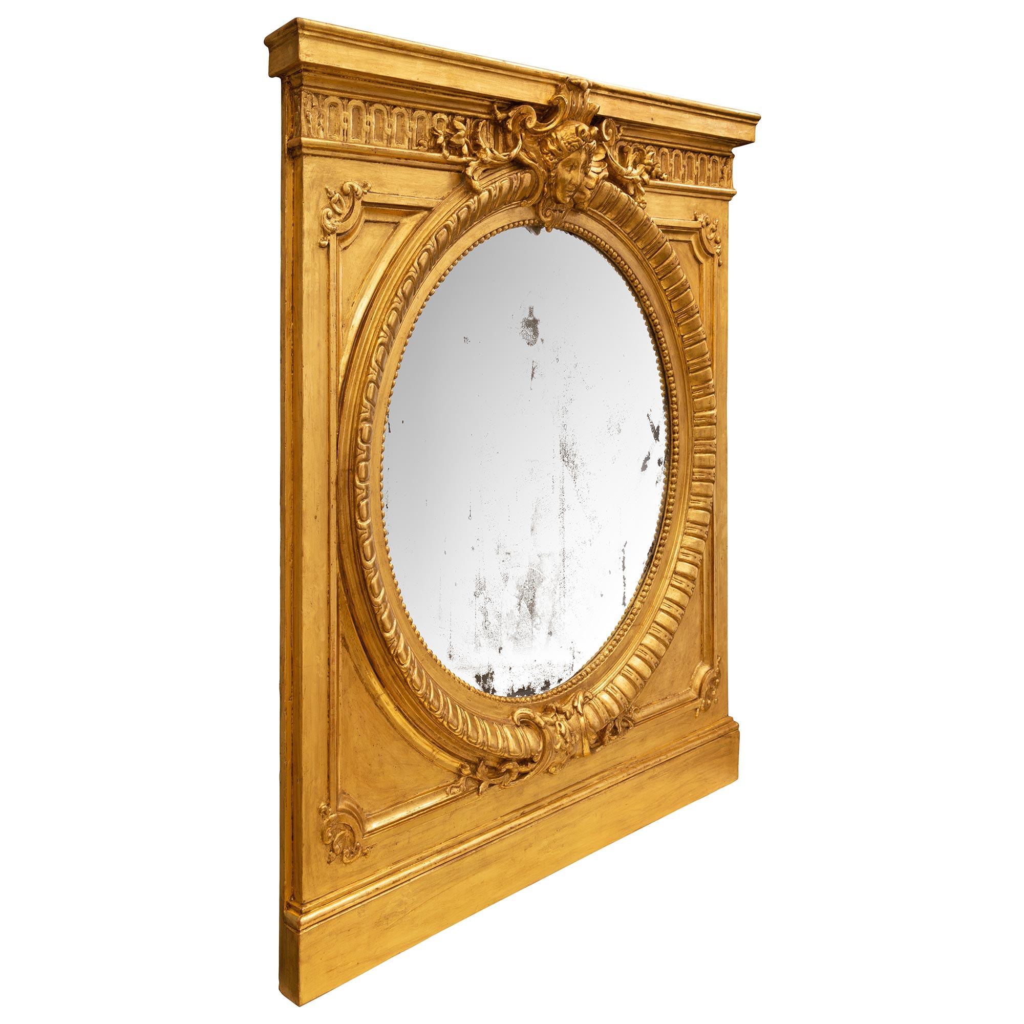 Un élégant et extrêmement décoratif miroir en bois doré de style Louis XVI du 19ème siècle. Au centre se trouve le miroir circulaire d'origine, encadré d'une fine bordure cannelée perlée et mouchetée. Le cadre présente une base droite avec un motif