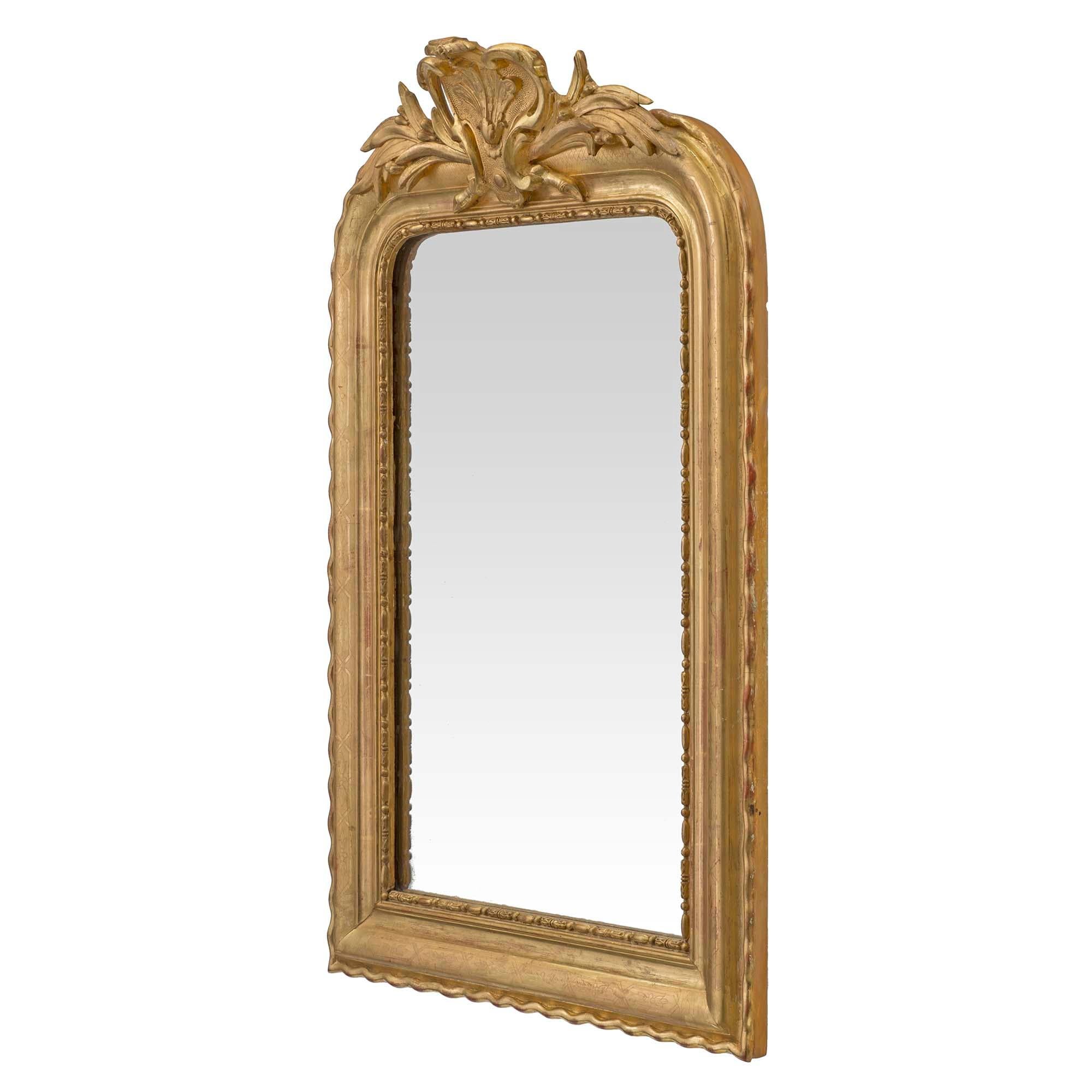 Precioso espejo francés de madera dorada de San Luis XVI del siglo XIX. La placa original del espejo está bordeada por un adorno con diseño de huevo y dardo dentro del espejo moldeado con bordes con volutas. En la atractiva corona superior hay una