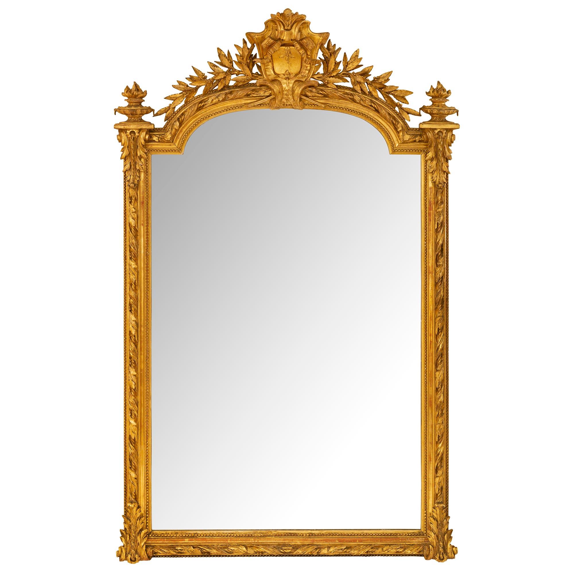 A most elegant French 19th century Louis XVI st. giltwood mirror. The mirror retains its original mirror plate set within a lovely finely carved wrap around beaded mottled border. A charming richly carved twisted foliate band extends throughout the