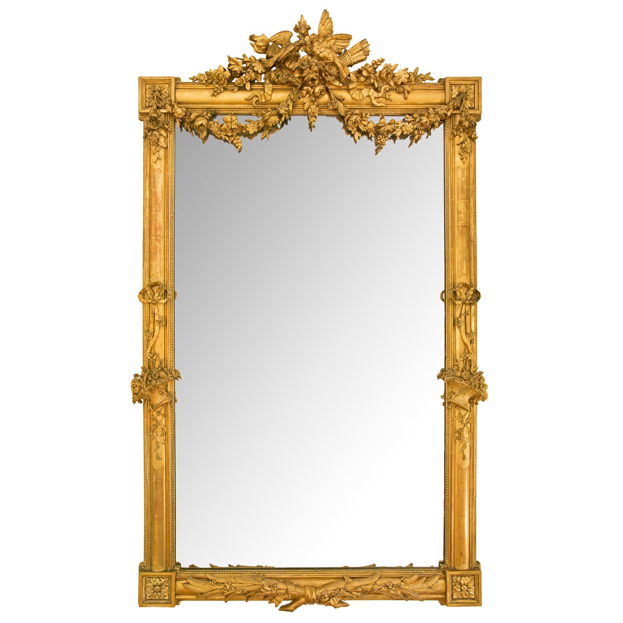 A most elegant French 19th century Louis XVI st. giltwood mirror. The mirror retains its original mirror plate framed within a fine Coeur de Rai border. The beautiful mottled frame displays richly carved block rosettes at each corner with superb