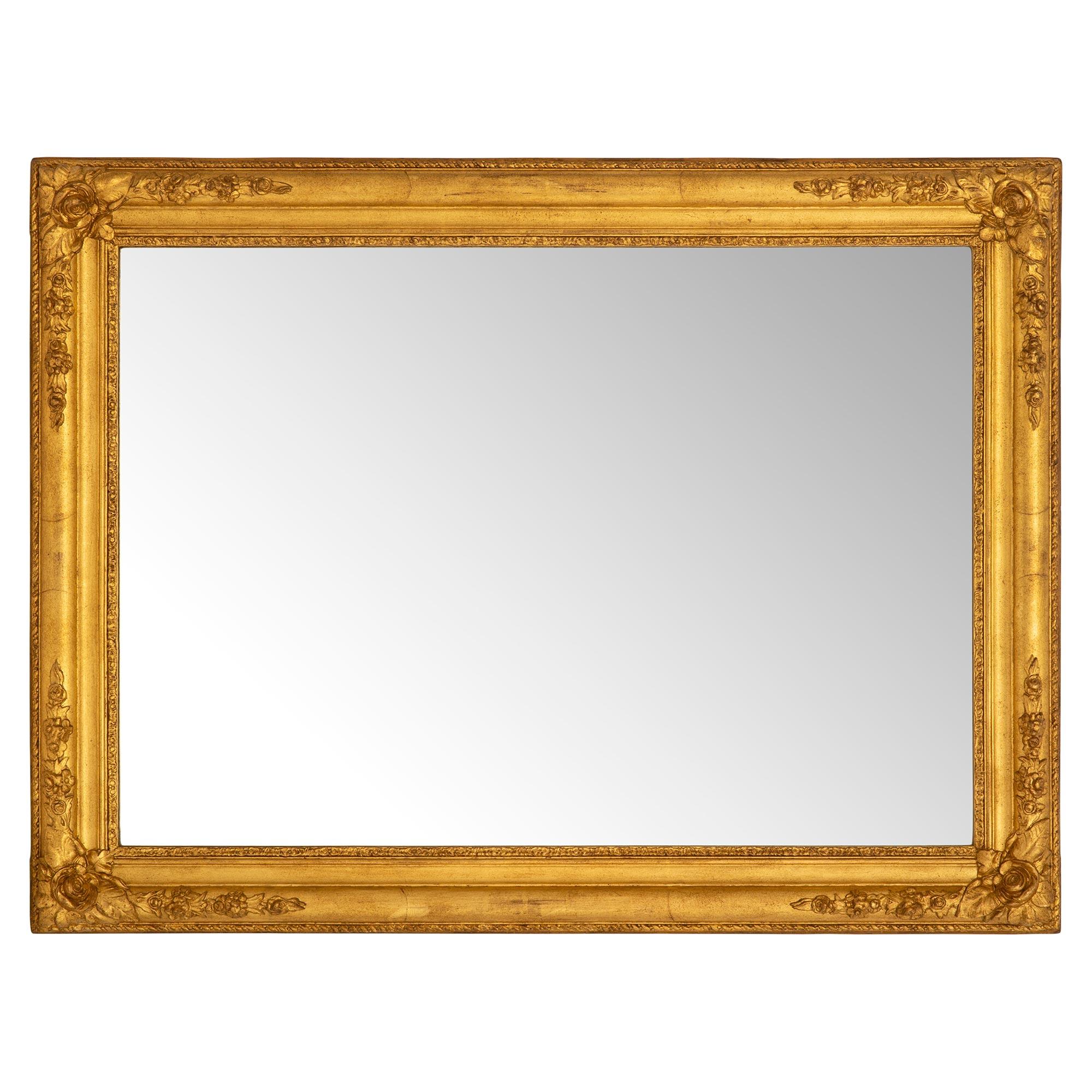 A most charming rectangular French 19th century Louis XVI st. giltwood mirror. The original mirror plate is set within a fine wraparound foliate and mottled frame. At each corner are beautiful extremely decorative floral and foliate reserves with