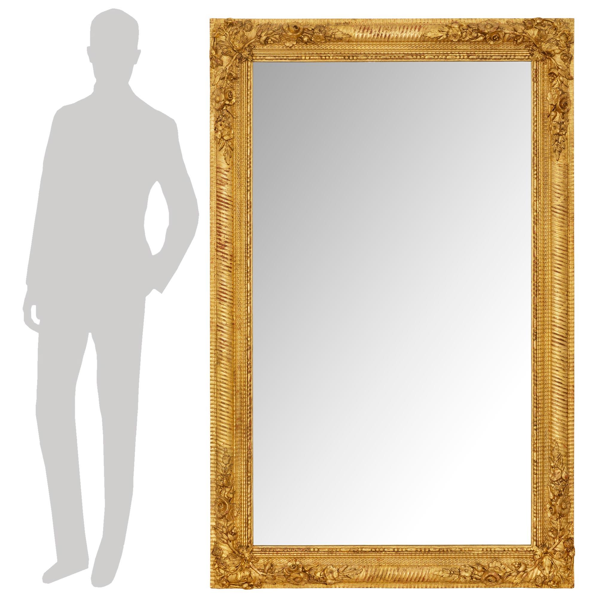 Magnifique miroir en bois doré de style Louis XVI du XIXe siècle. Le miroir rectangulaire d'origine est placé dans un cadre en bois doré avec une garniture intérieure perlée et un motif d'écailles de poisson. La bande extérieure est ornée d'un nez